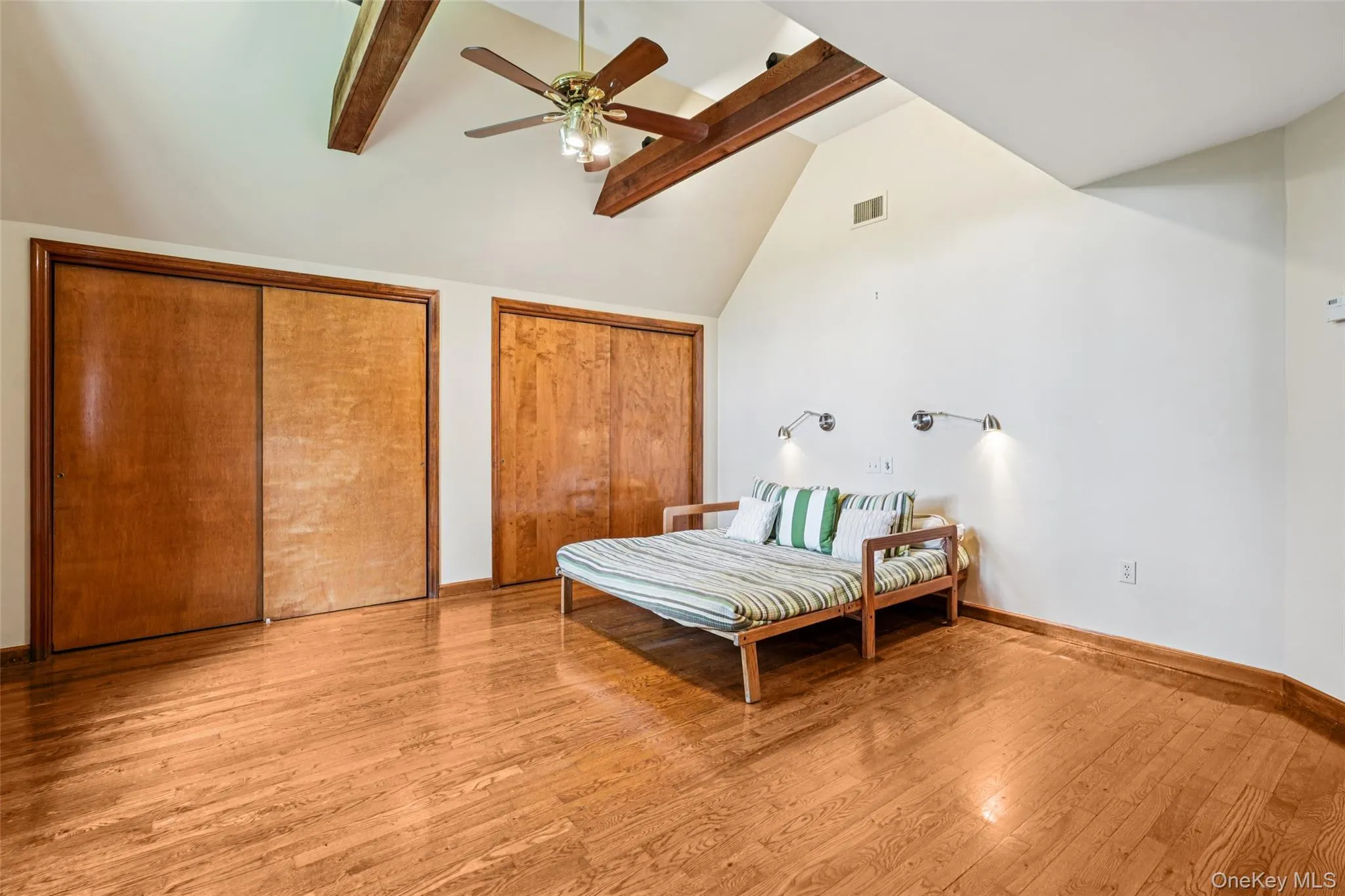 Bedroom with multiple closets, beam ceiling, wood finished floors, high vaulted ceiling, and ceiling fan Bedroom with multiple closets, beam ceiling, wood finished floors, high vaulted ceiling, and ceiling fan
