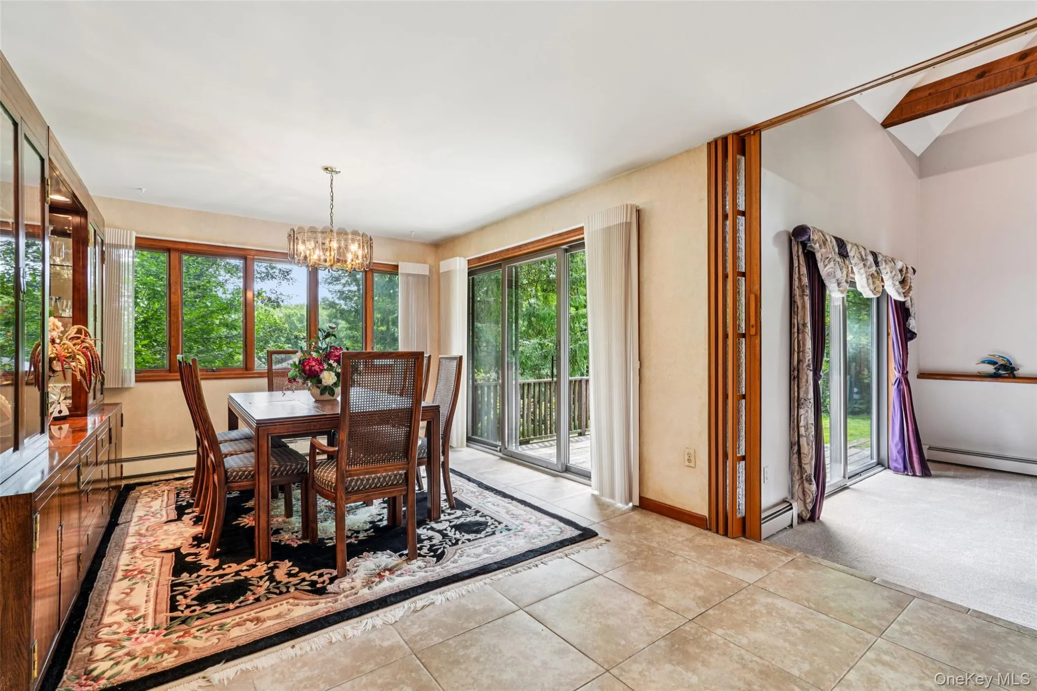 Tiled dining area with a chandelier, a baseboard radiator, and lofted ceiling Tiled dining area with a chandelier, a baseboard radiator, and lofted ceiling