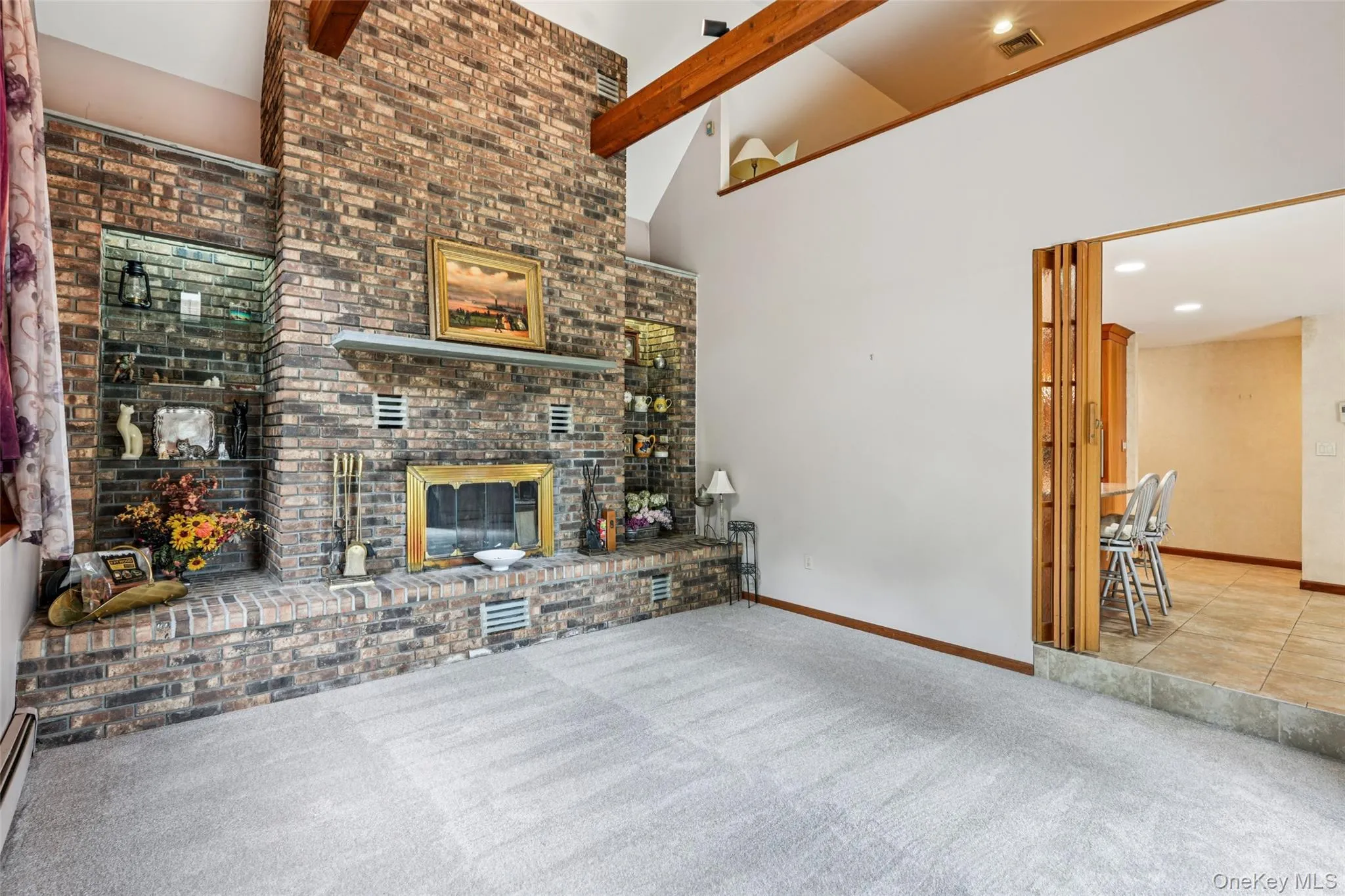 Unfurnished living room with carpet flooring, high vaulted ceiling, beamed ceiling, a fireplace, and baseboard heating Unfurnished living room with carpet flooring, high vaulted ceiling, beamed ceiling, a fireplace, and baseboard heating