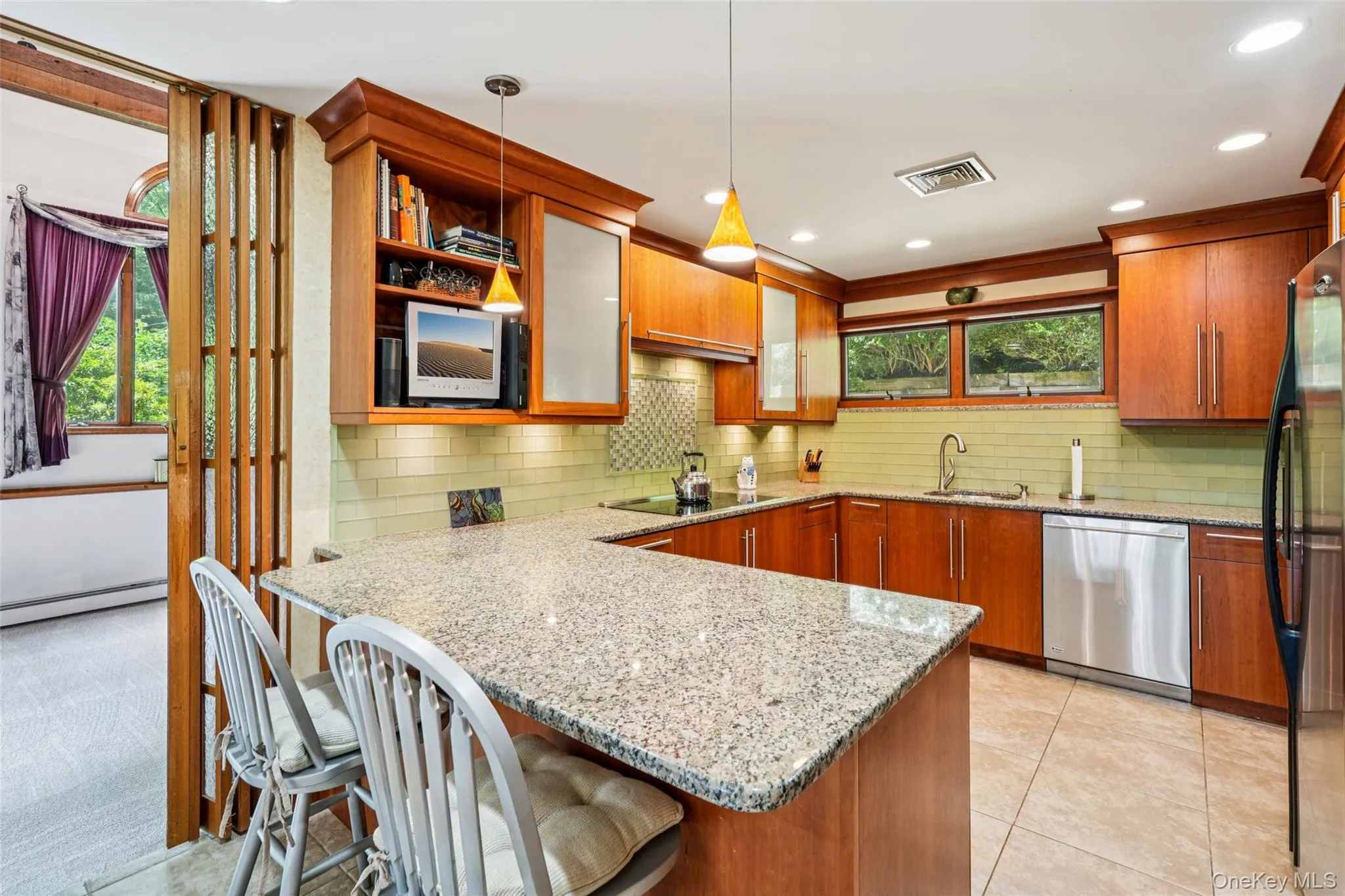 Kitchen featuring stainless steel dishwasher, freestanding refrigerator, healthy amount of natural light, a peninsula, and recessed lighting Kitchen featuring stainless steel dishwasher, freestanding refrigerator, healthy amount of natural light, a peninsula, and recessed lighting