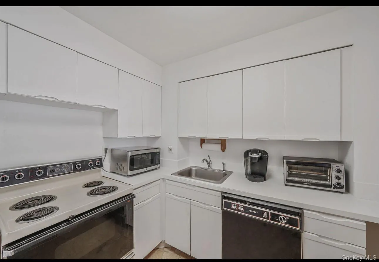 Kitchen featuring white electric range, light countertops, dishwasher, white cabinetry, and stainless steel microwave Kitchen featuring white electric range, light countertops, dishwasher, white cabinetry, and stainless steel microwave