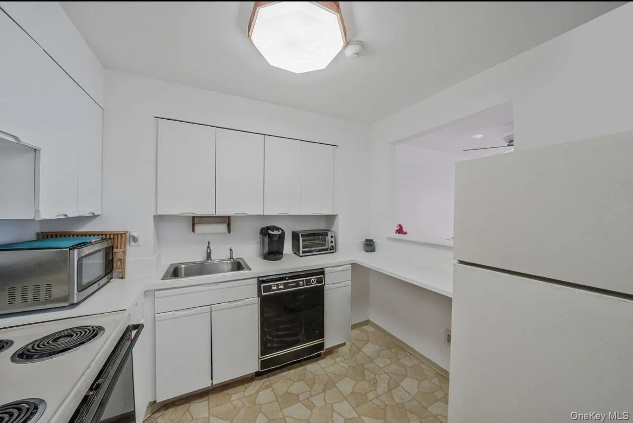 Kitchen featuring white appliances, light countertops, and white cabinets Kitchen featuring white appliances, light countertops, and white cabinets