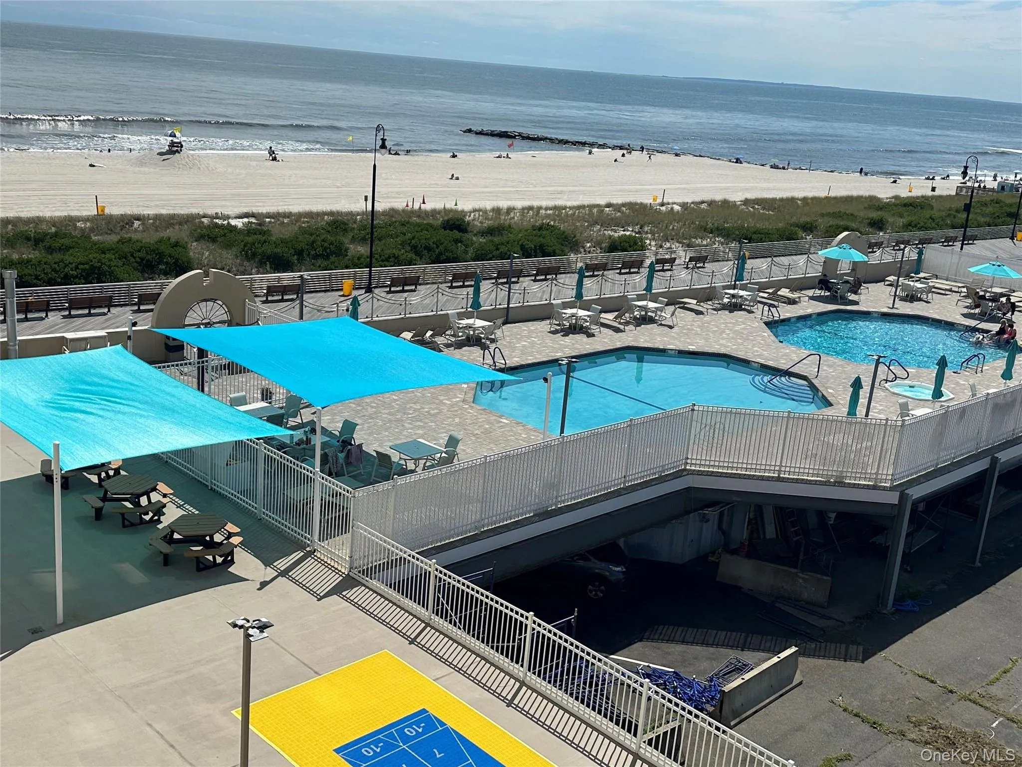 Community pool featuring a patio and view of water and beach Community pool featuring a patio and view of water and beach