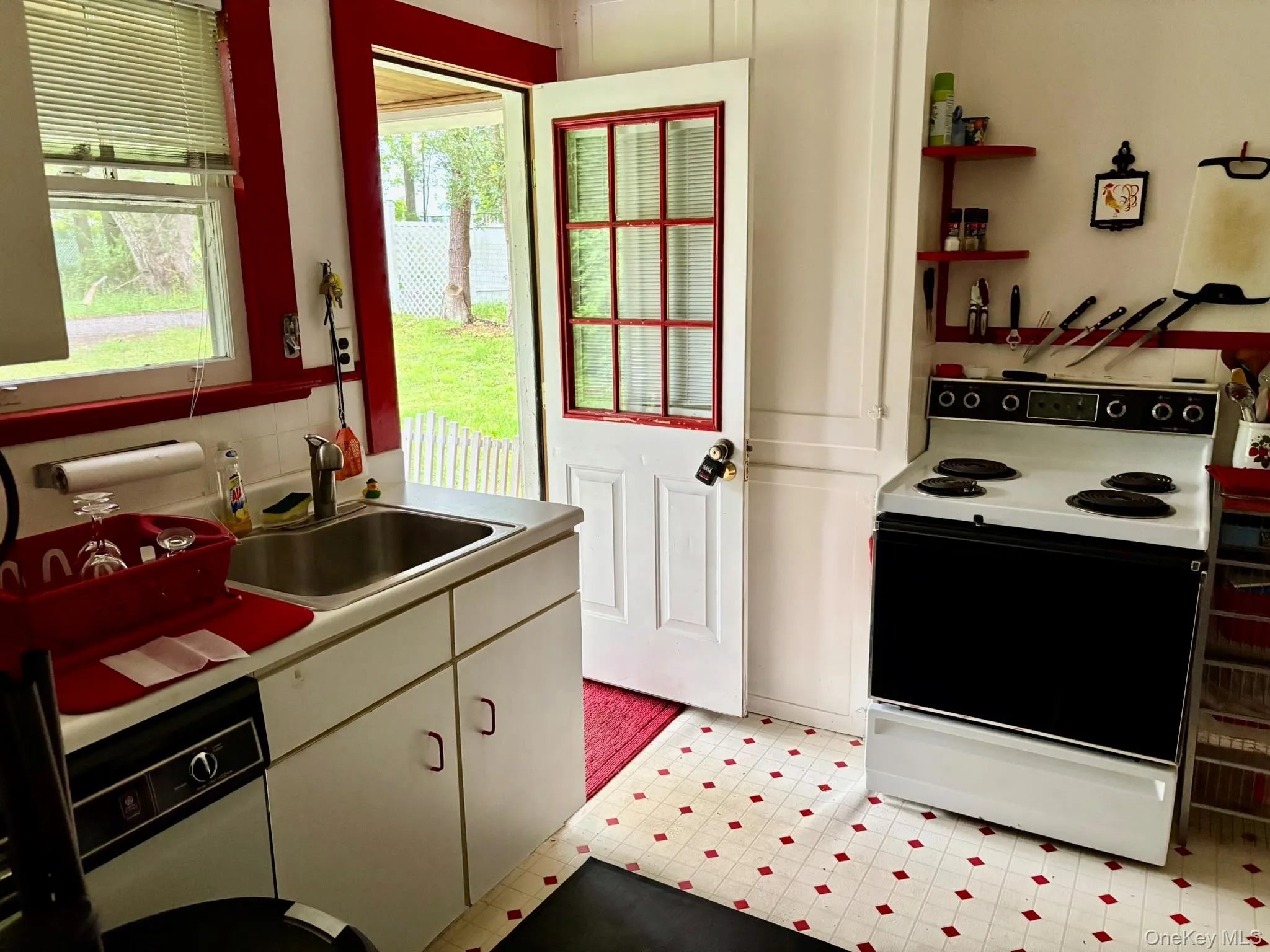 Kitchen featuring electric range oven, a sink, light countertops, and light flooring Kitchen featuring electric range oven, a sink, light countertops, and light flooring
