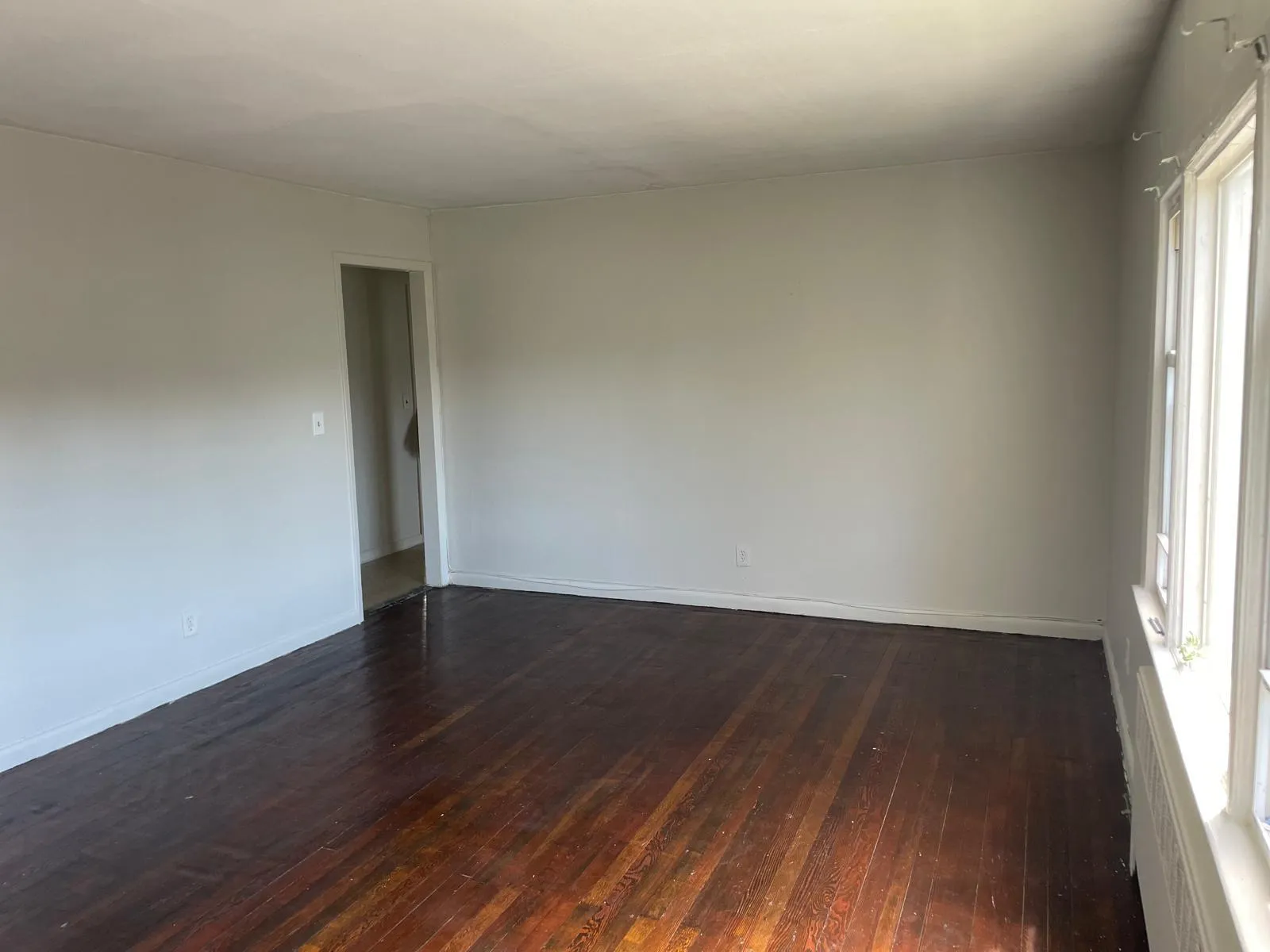 Spare room with dark wood-type flooring and baseboards Spare room with dark wood-type flooring and baseboards