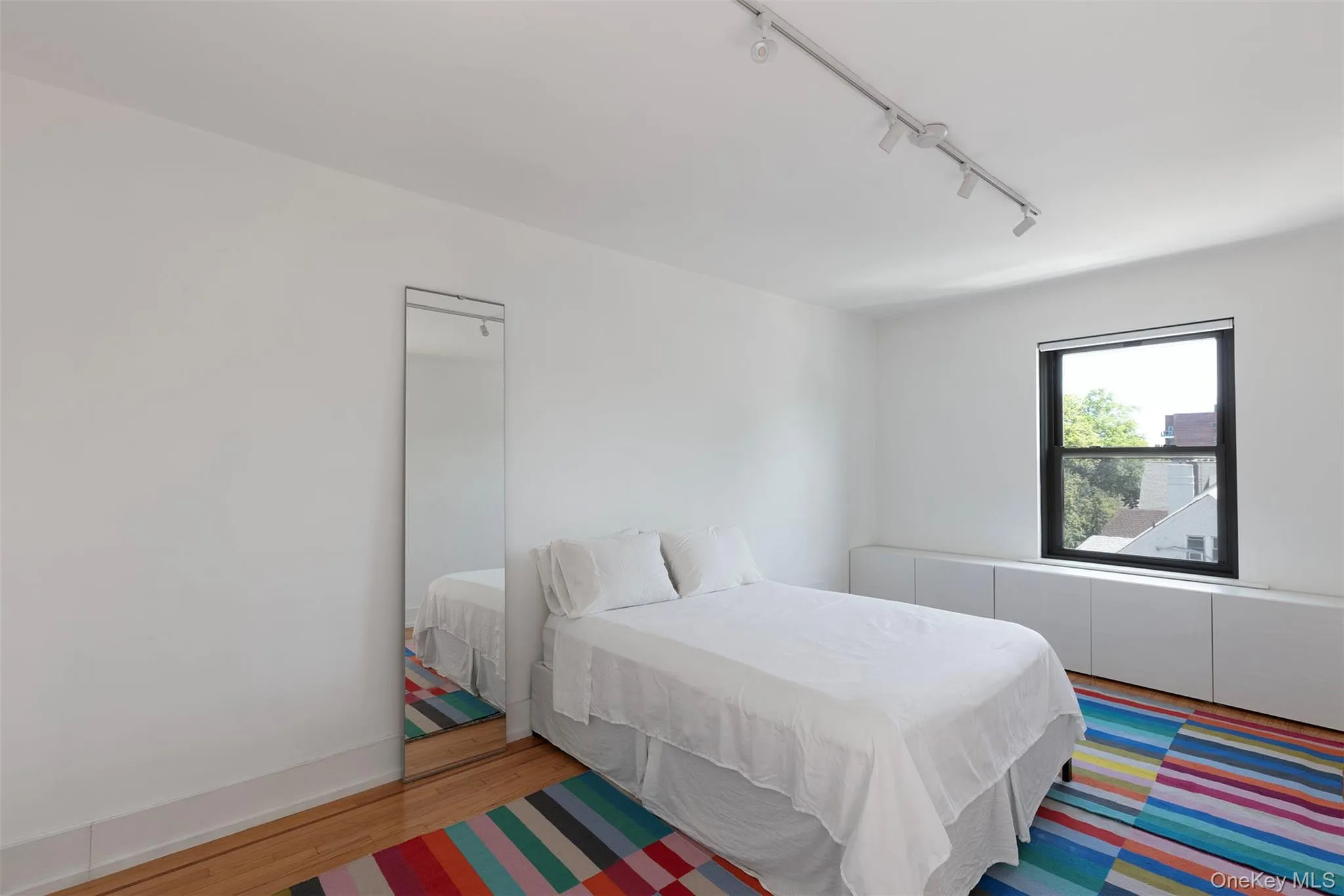 Bedroom featuring rail lighting and wood finished floors Bedroom featuring rail lighting and wood finished floors