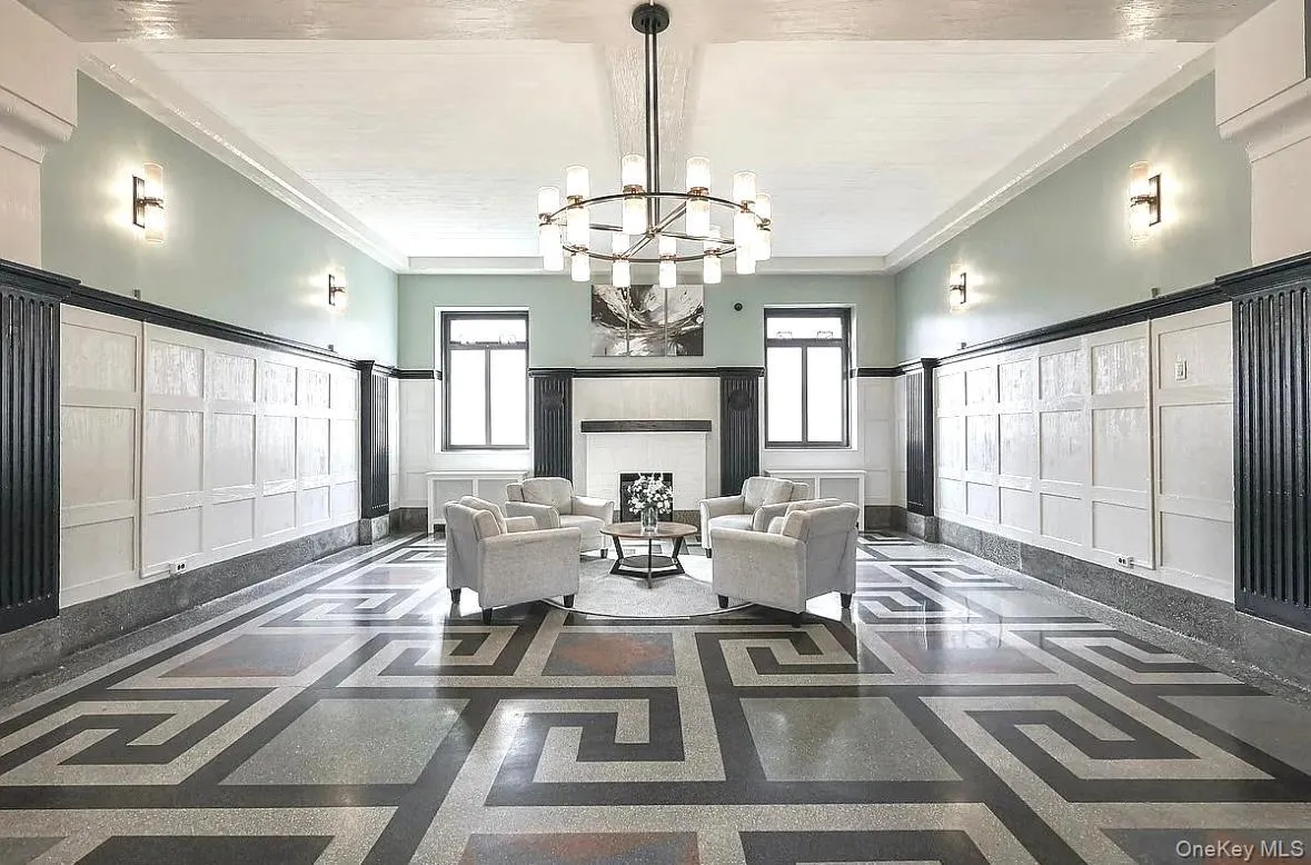 Living room featuring a decorative wall, inlaid floor details, a chandelier, plenty of natural light, and crown molding Living room featuring a decorative wall, inlaid floor details, a chandelier, plenty of natural light, and crown molding