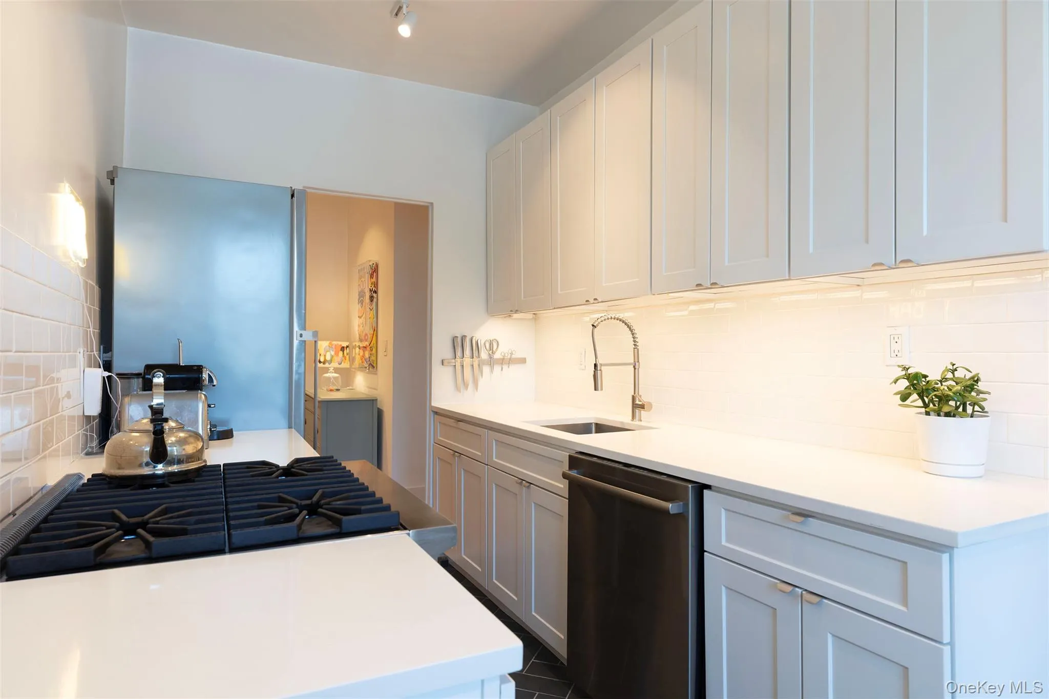 Kitchen featuring dishwasher, a sink, backsplash, light countertops, and cooktop Kitchen featuring dishwasher, a sink, backsplash, light countertops, and cooktop