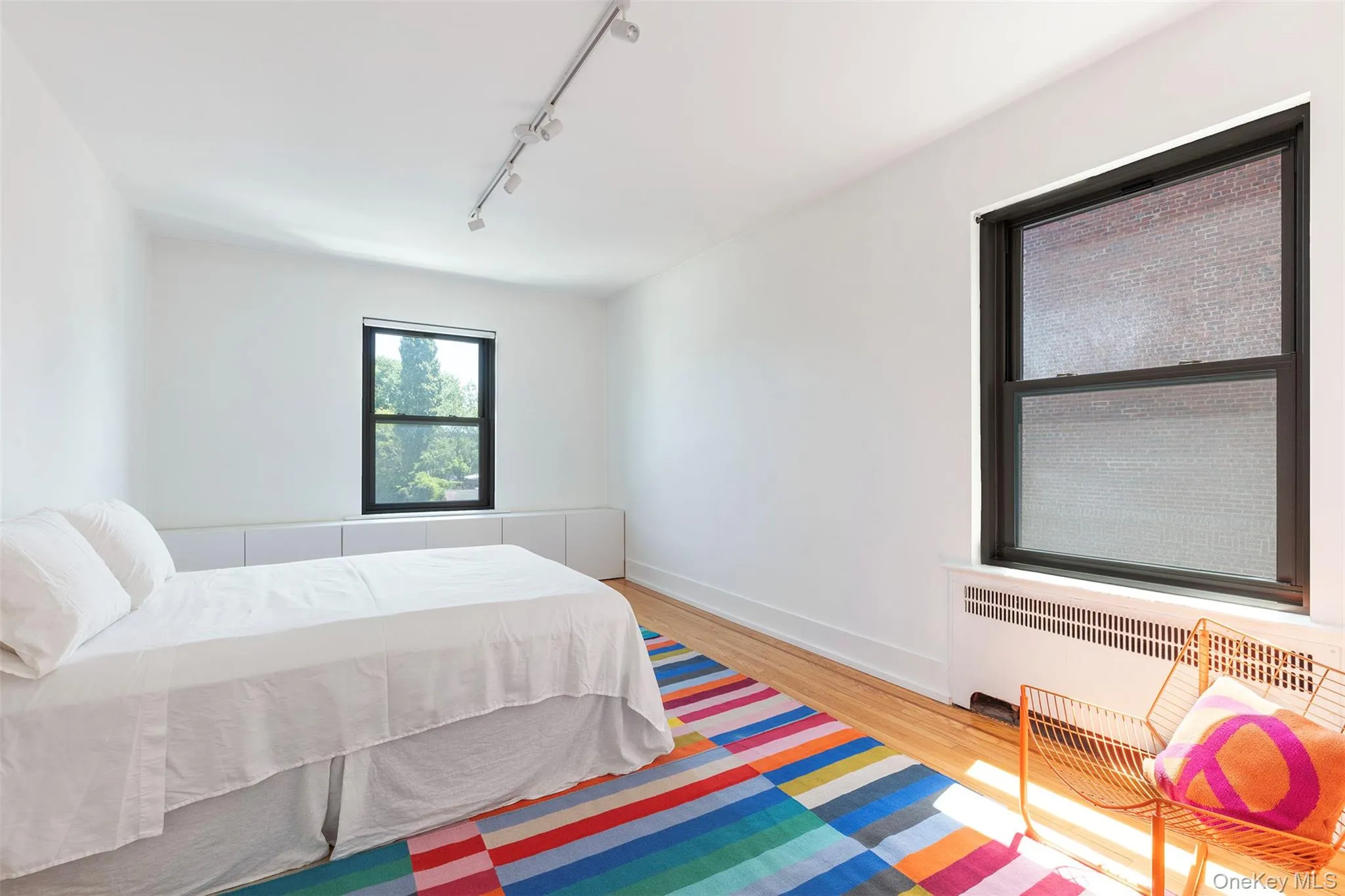 Bedroom featuring rail lighting, wood finished floors, and baseboards Bedroom featuring rail lighting, wood finished floors, and baseboards