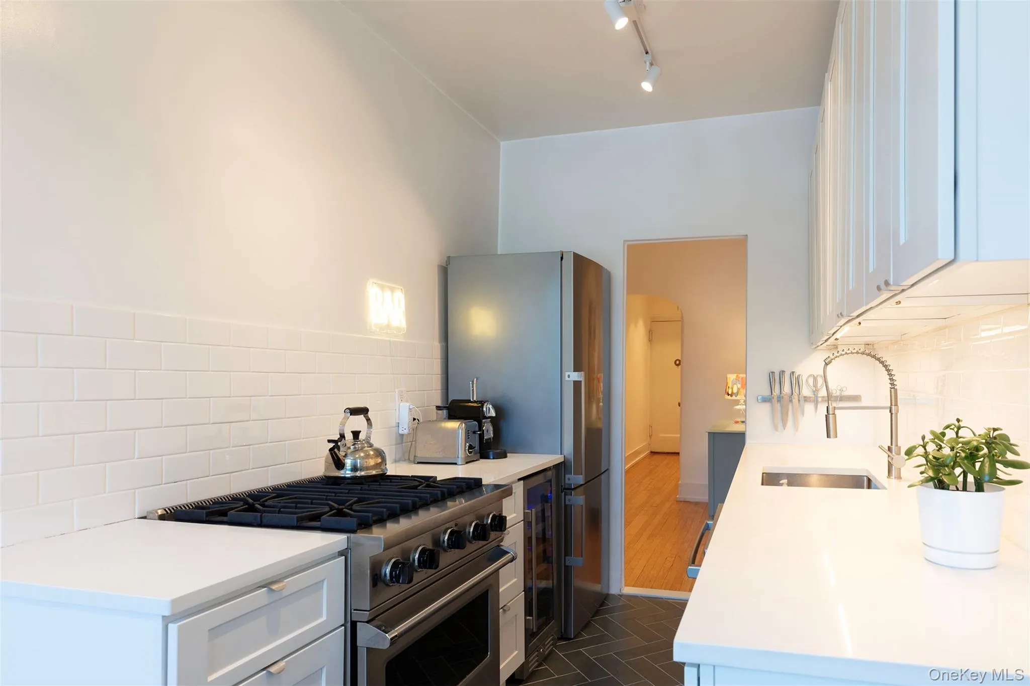 Kitchen with a sink, appliances with stainless steel finishes, arched walkways, light countertops, and decorative backsplash Kitchen with a sink, appliances with stainless steel finishes, arched walkways, light countertops, and decorative backsplash