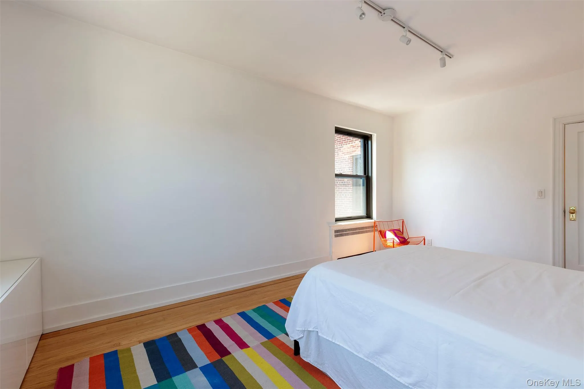 Bedroom with rail lighting, wood finished floors, and baseboards Bedroom with rail lighting, wood finished floors, and baseboards