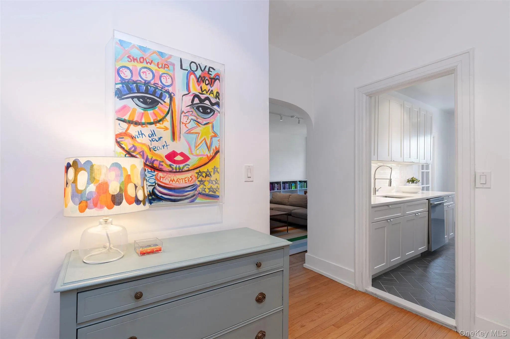 Corridor with a sink, light wood finished floors, arched walkways, and baseboards Corridor with a sink, light wood finished floors, arched walkways, and baseboards