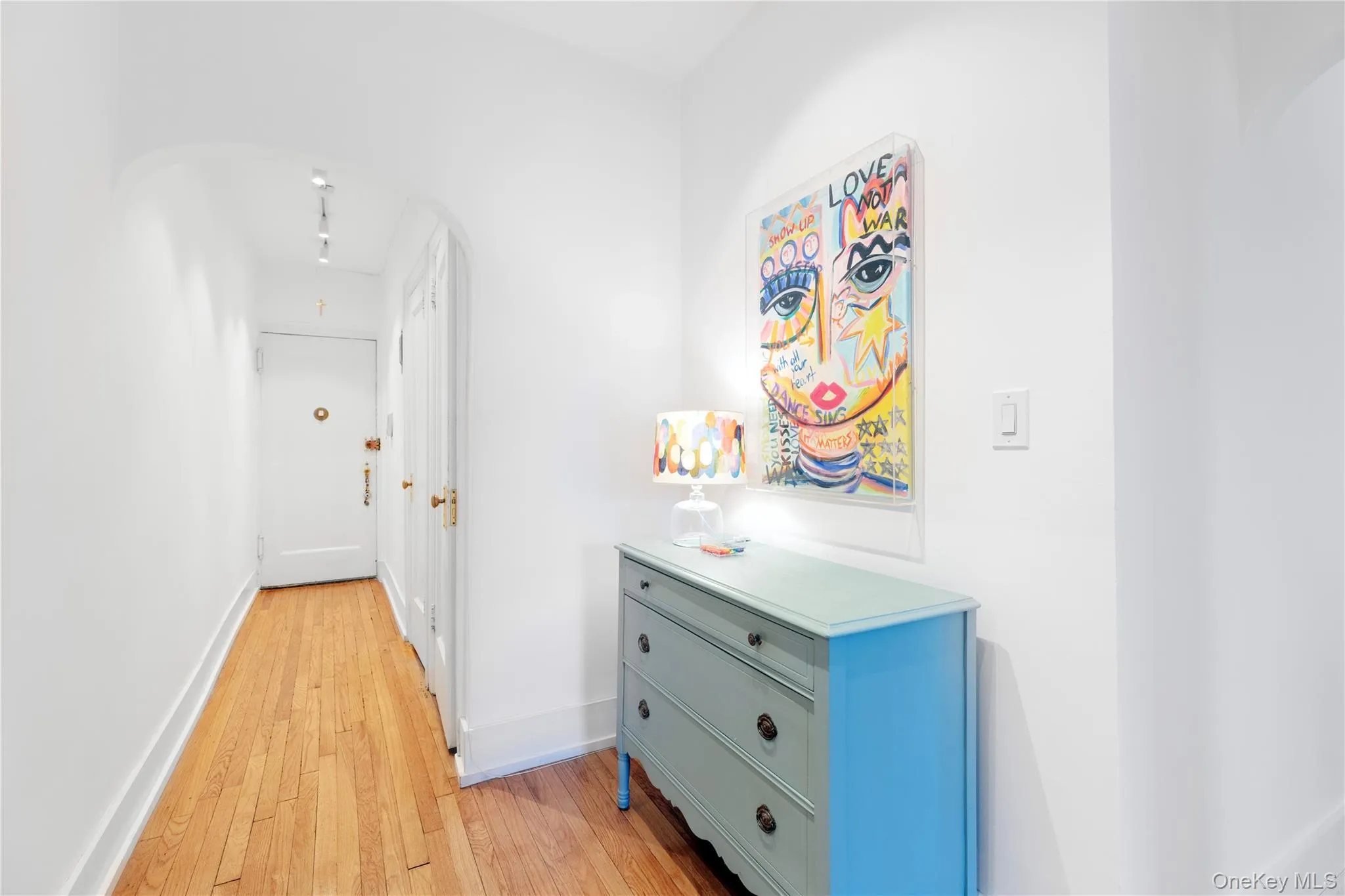 Hallway featuring arched walkways, light wood-style flooring, and baseboards Hallway featuring arched walkways, light wood-style flooring, and baseboards