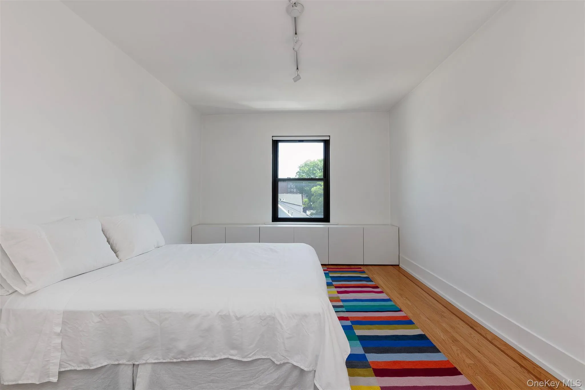Bedroom with wood finished floors, rail lighting, and baseboards Bedroom with wood finished floors, rail lighting, and baseboards