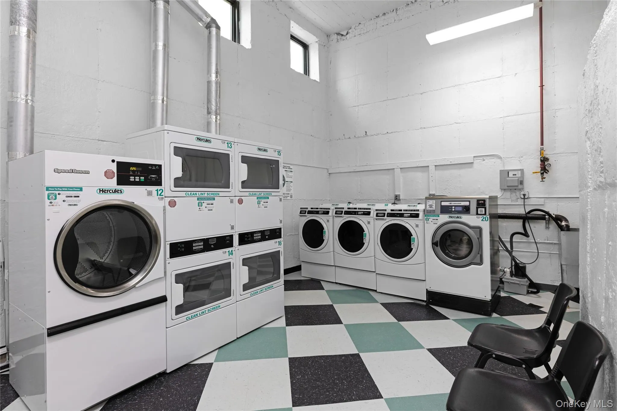 Shared laundry room with tile patterned floors, independent washer and dryer, estacked washer and dryer, and concrete block wall Shared laundry room with tile patterned floors, independent washer and dryer, estacked washer and dryer, and concrete block wall