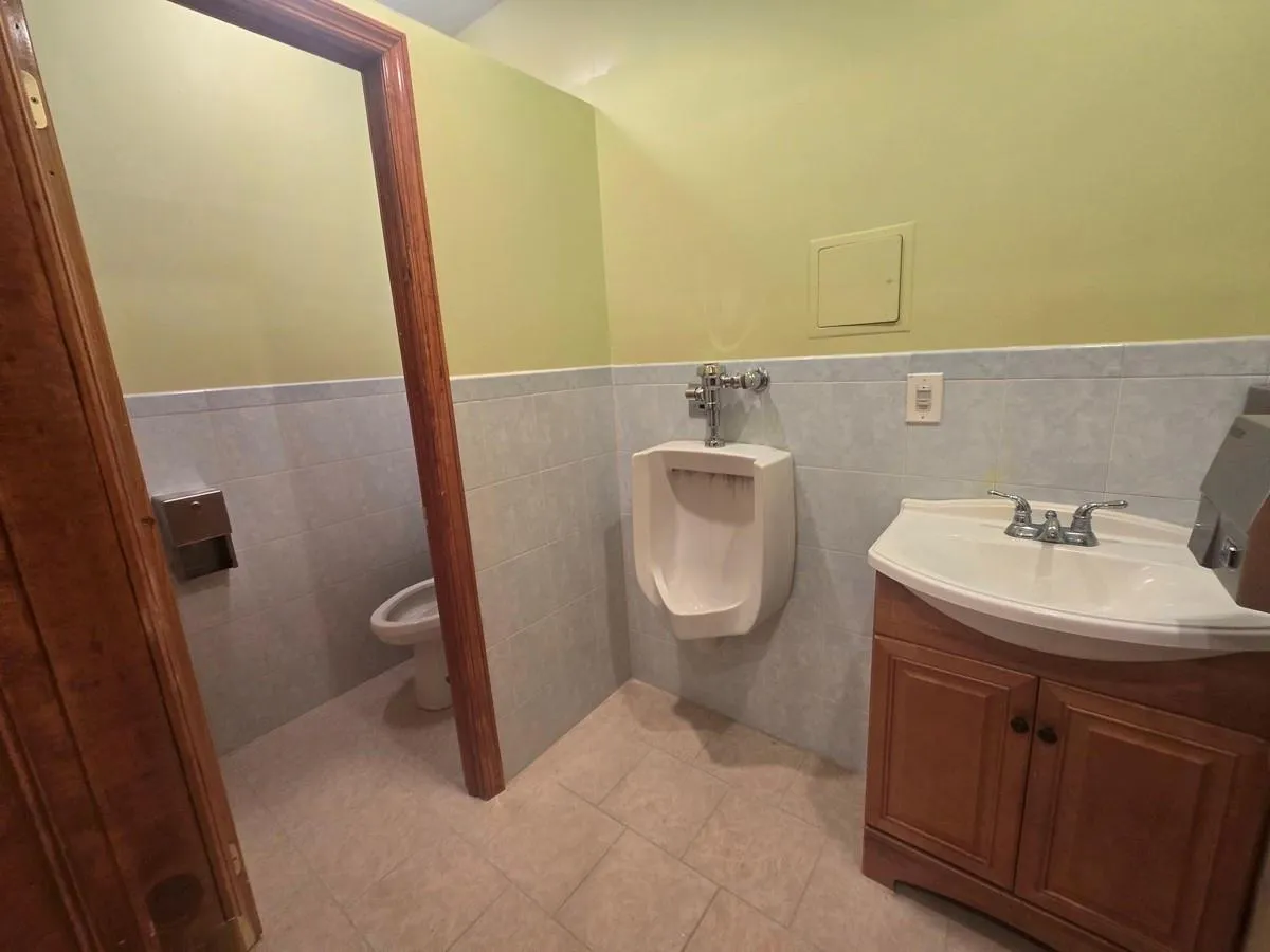 Bathroom featuring wainscoting, vanity, toilet, tile walls, and tile patterned flooring Bathroom featuring wainscoting, vanity, toilet, tile walls, and tile patterned flooring