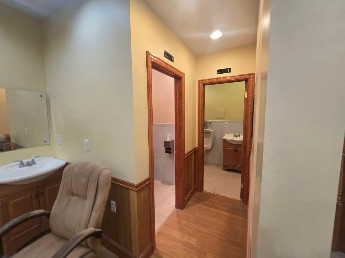 Full bathroom with a wainscoted wall, two vanities, and wood finished floors Full bathroom with a wainscoted wall, two vanities, and wood finished floors