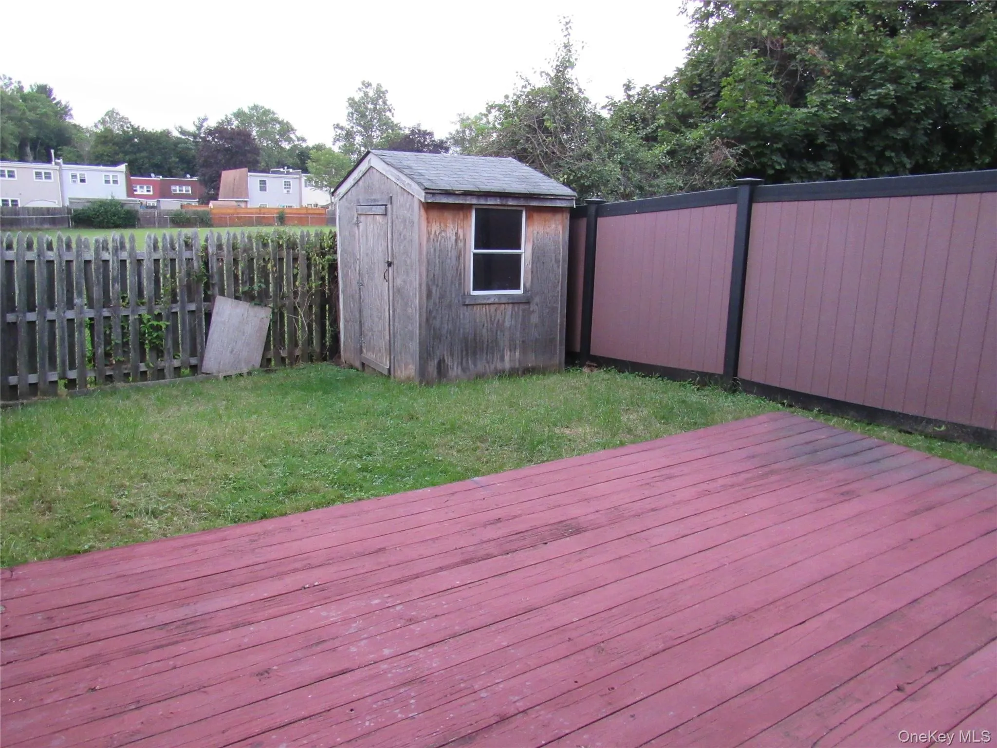 Wooden terrace with a fenced backyard and a storage shed Wooden terrace with a fenced backyard and a storage shed