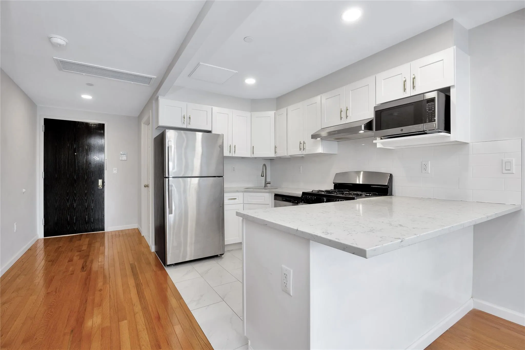 Kitchen featuring light stone countertops, white cabinetry, a peninsula, and stainless steel appliances Kitchen featuring light stone countertops, white cabinetry, a peninsula, and stainless steel appliances