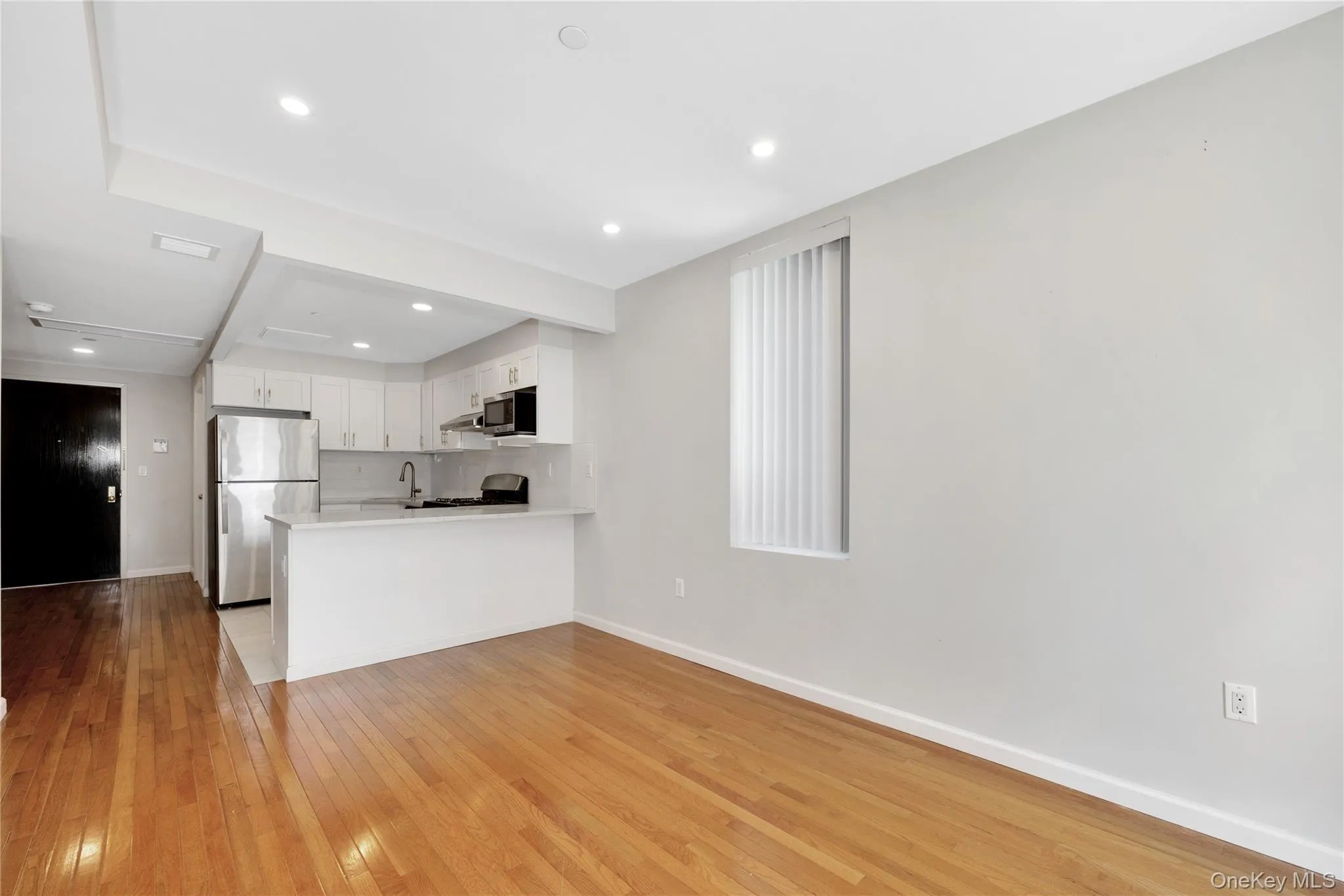 Kitchen with white cabinets, light countertops, light wood-type flooring, a peninsula, and stainless steel appliances Kitchen with white cabinets, light countertops, light wood-type flooring, a peninsula, and stainless steel appliances