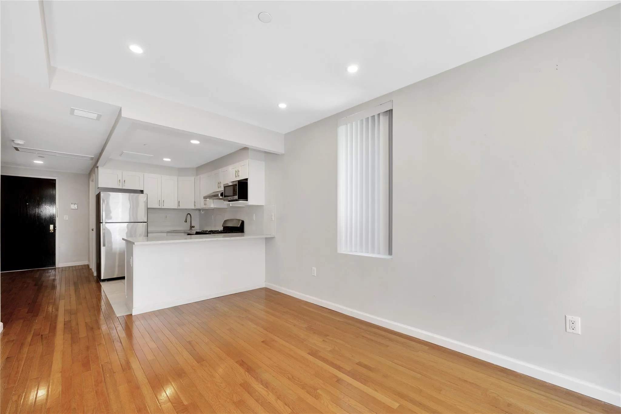 Kitchen with white cabinets, light countertops, light wood-type flooring, a peninsula, and stainless steel appliances Kitchen with white cabinets, light countertops, light wood-type flooring, a peninsula, and stainless steel appliances