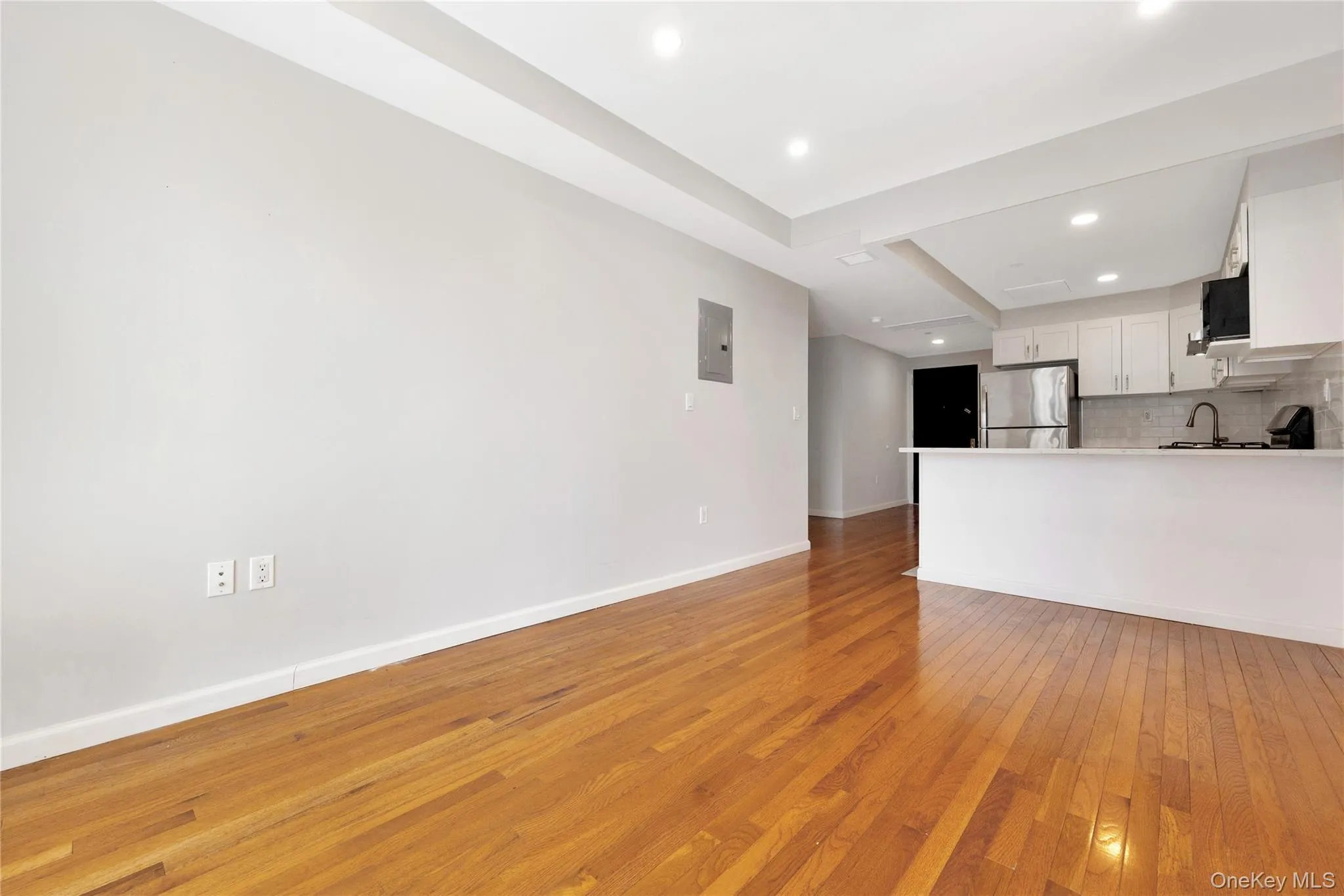 Kitchen featuring light wood-style floors, freestanding refrigerator, tasteful backsplash, white cabinetry, and baseboards Kitchen featuring light wood-style floors, freestanding refrigerator, tasteful backsplash, white cabinetry, and baseboards