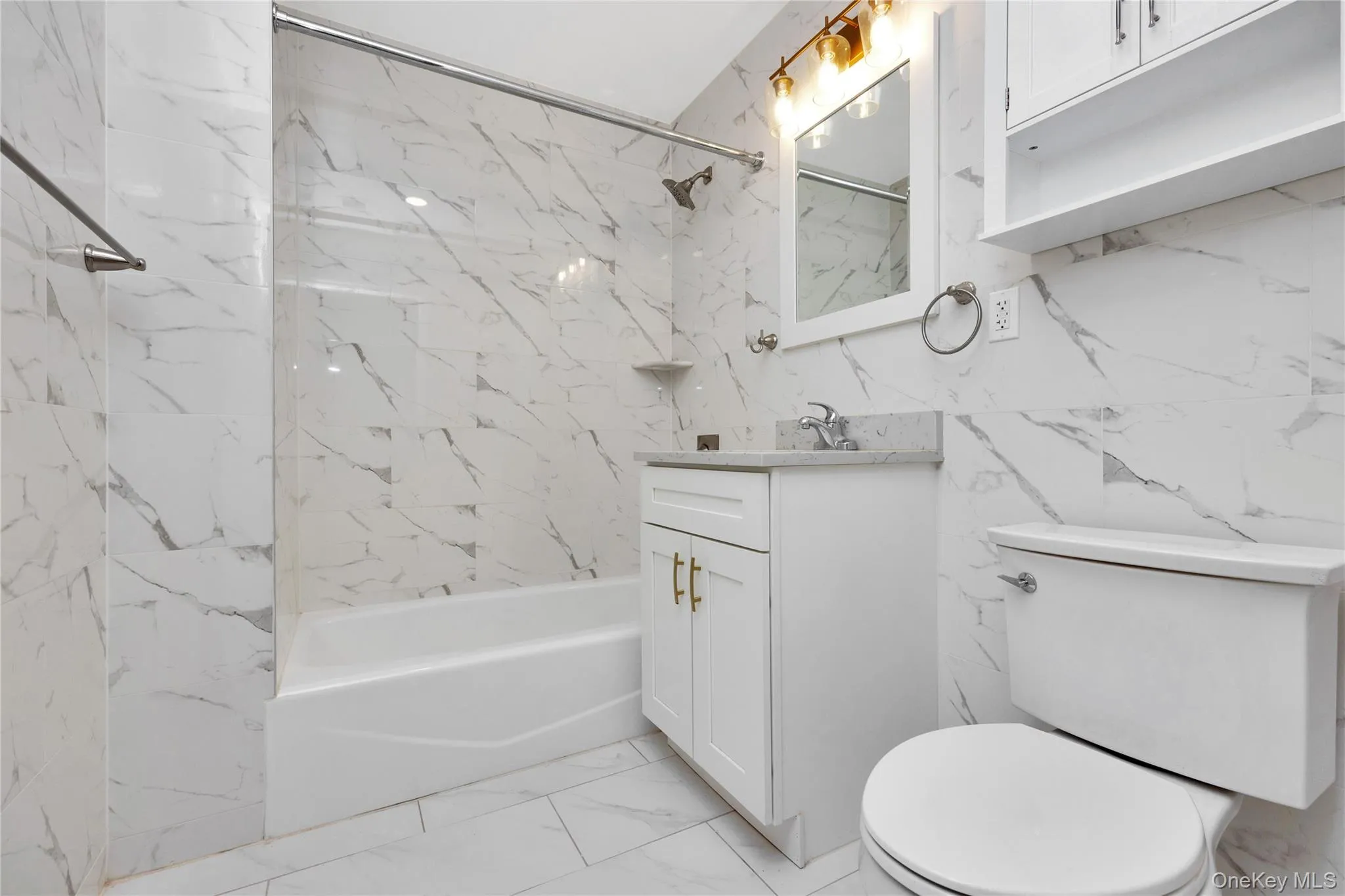 Bathroom featuring toilet, stone wall, shower / bathing tub combination, vanity, and marble finish floor Bathroom featuring toilet, stone wall, shower / bathing tub combination, vanity, and marble finish floor