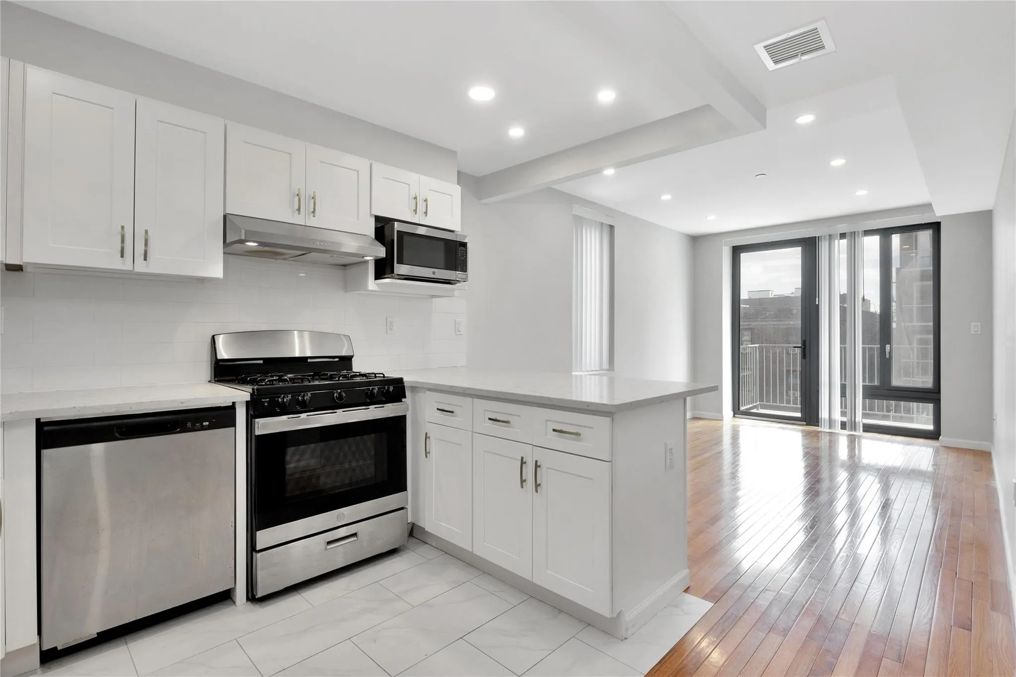 Kitchen featuring visible vents, appliances with stainless steel finishes, a peninsula, under cabinet range hood, and decorative backsplash Kitchen featuring visible vents, appliances with stainless steel finishes, a peninsula, under cabinet range hood, and decorative backsplash