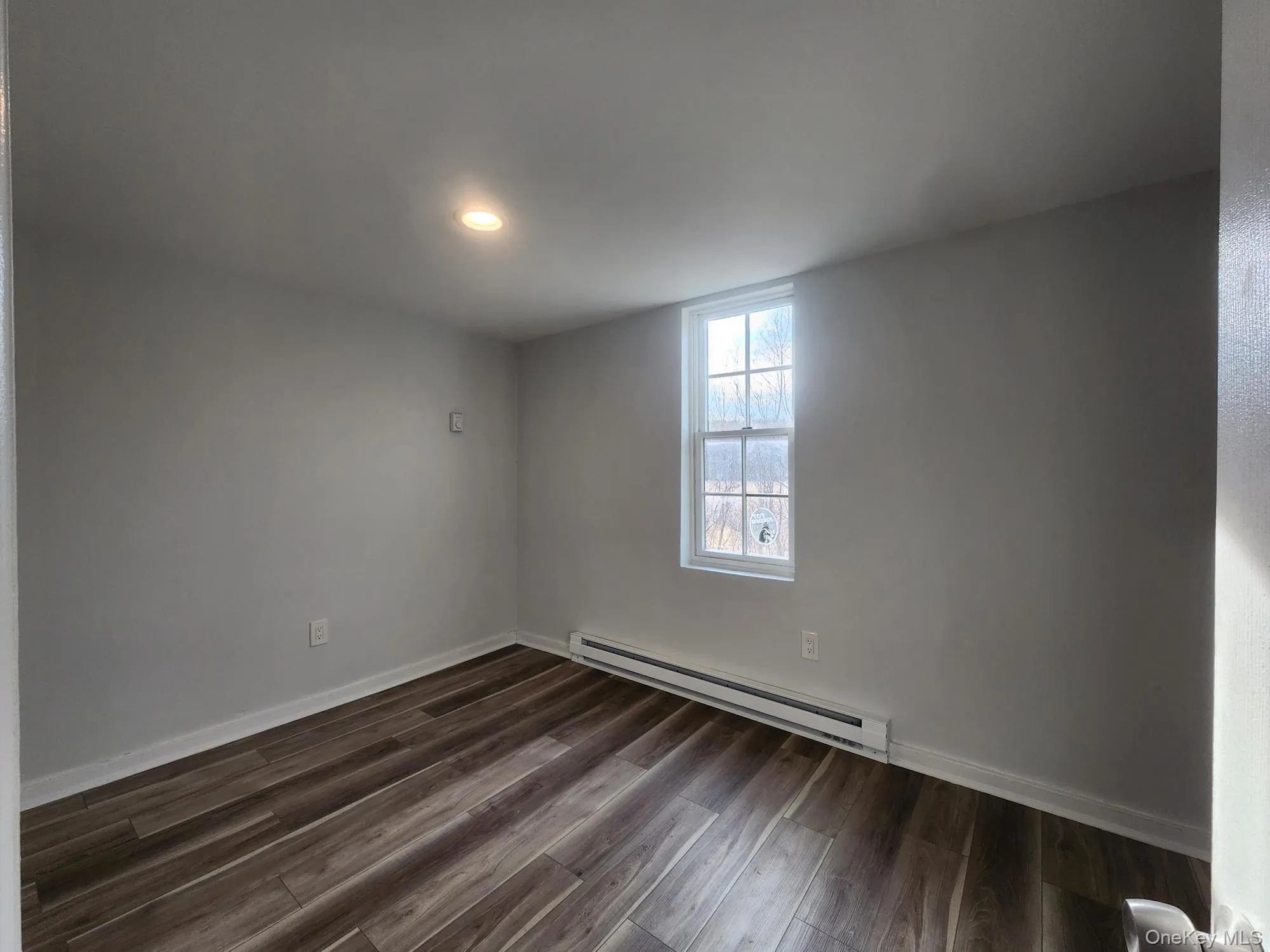 Unfurnished room featuring baseboard heating, dark wood-type flooring, baseboards, and recessed lighting Unfurnished room featuring baseboard heating, dark wood-type flooring, baseboards, and recessed lighting