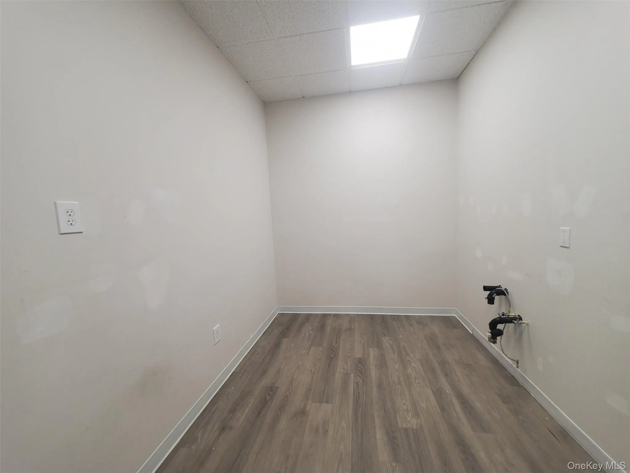 Laundry area with baseboards and dark wood-style floors Laundry area with baseboards and dark wood-style floors