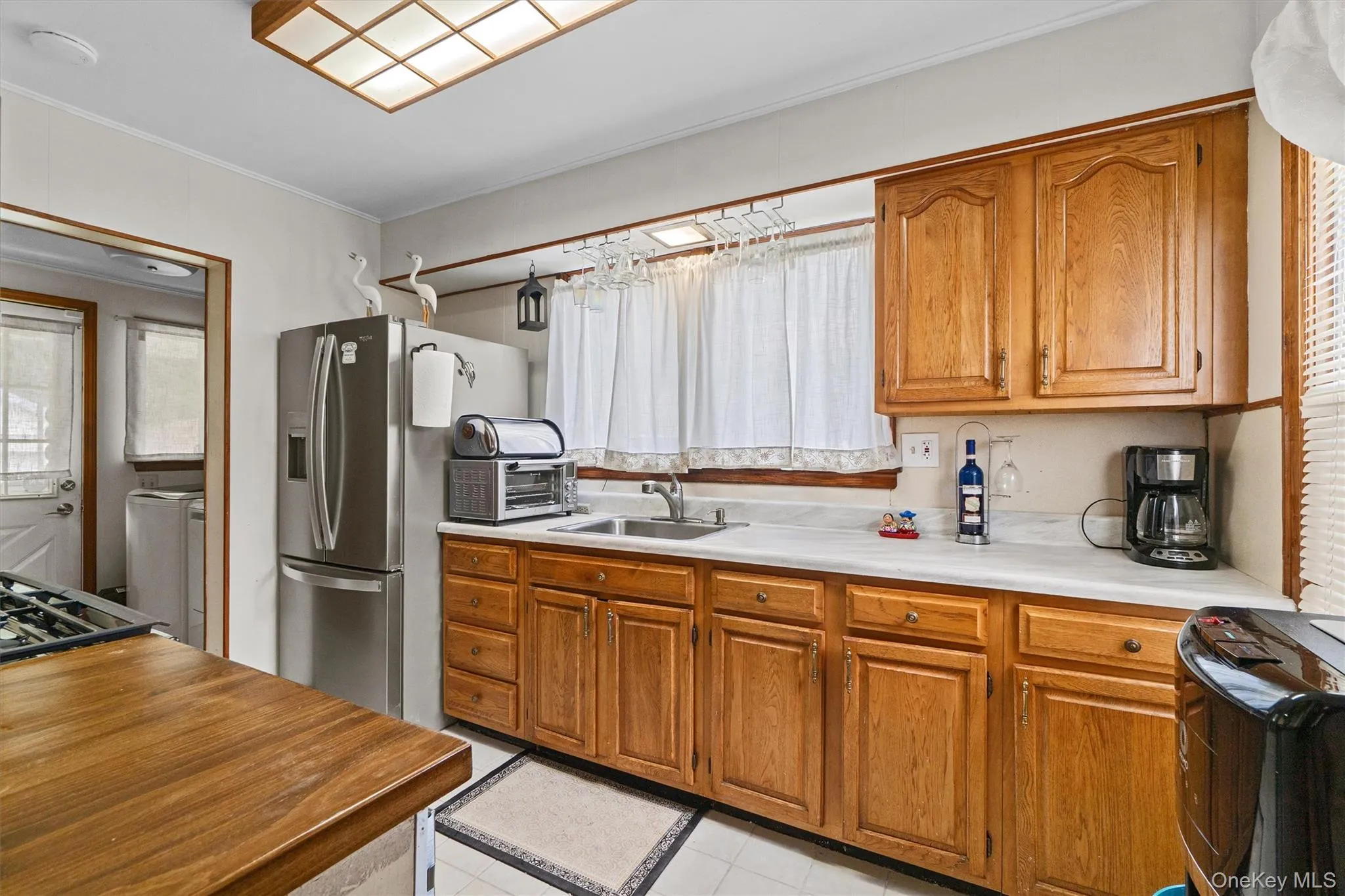 Kitchen with a sink, brown cabinetry, light tile patterned flooring, and dishwasher. Kitchen with a sink, brown cabinetry, light tile patterned flooring, and dishwasher.