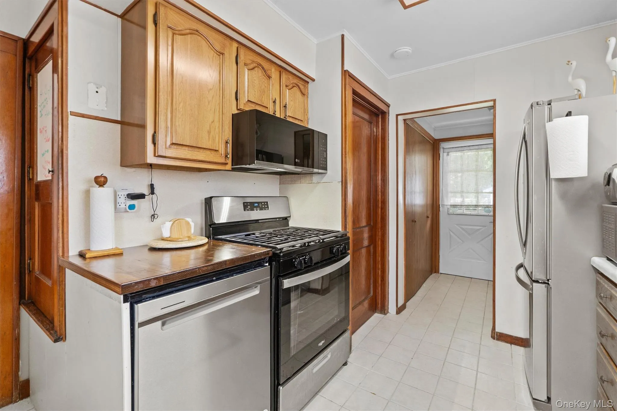 Kitchen with a sink, brown cabinetry, light tile patterned flooring, and stainless steel appliances. Kitchen with a sink, brown cabinetry, light tile patterned flooring, and stainless steel appliances.