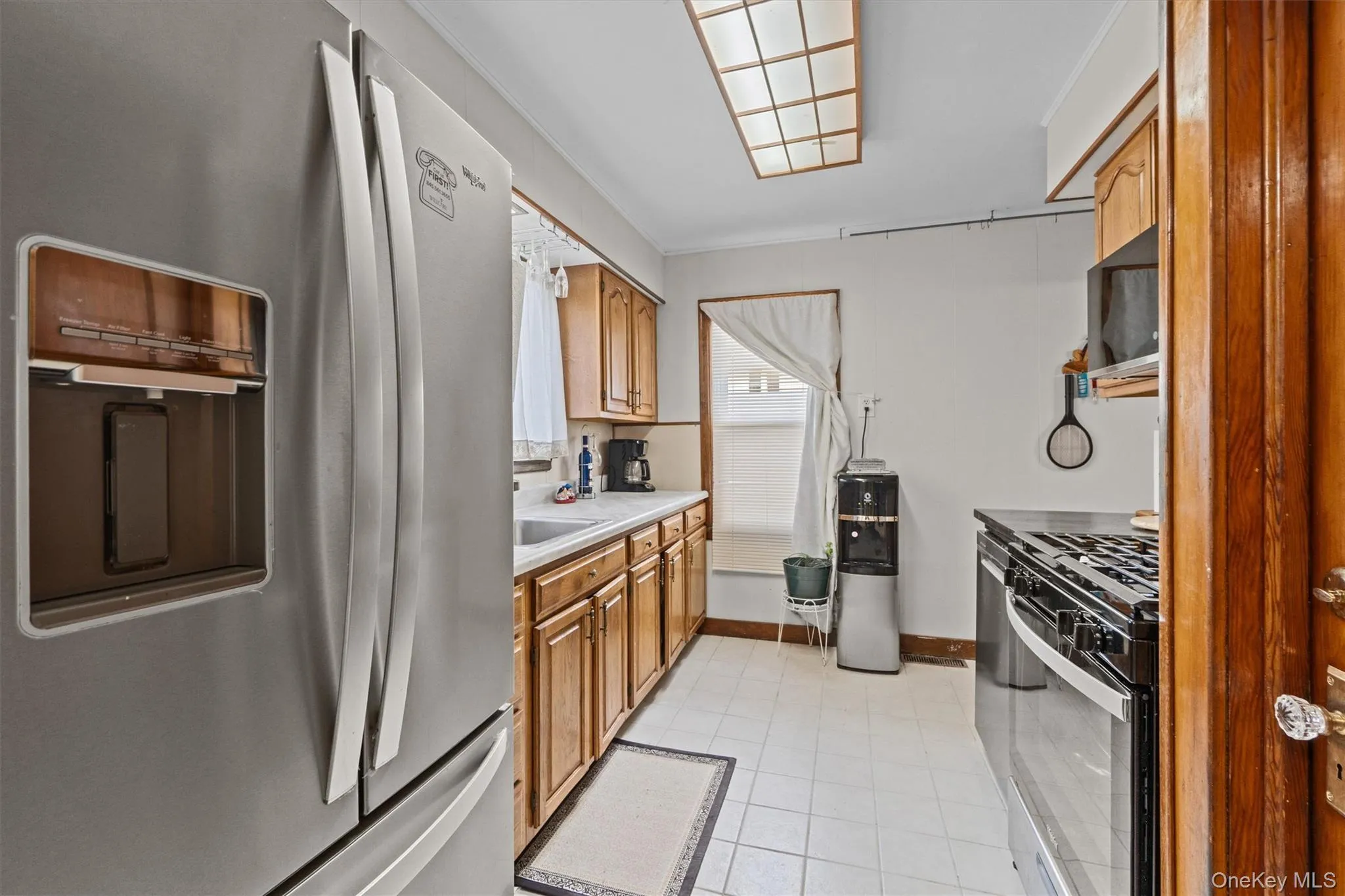 Kitchen with a sink, brown cabinetry, light tile patterned flooring, and stainless steel appliances. Kitchen with a sink, brown cabinetry, light tile patterned flooring, and stainless steel appliances.