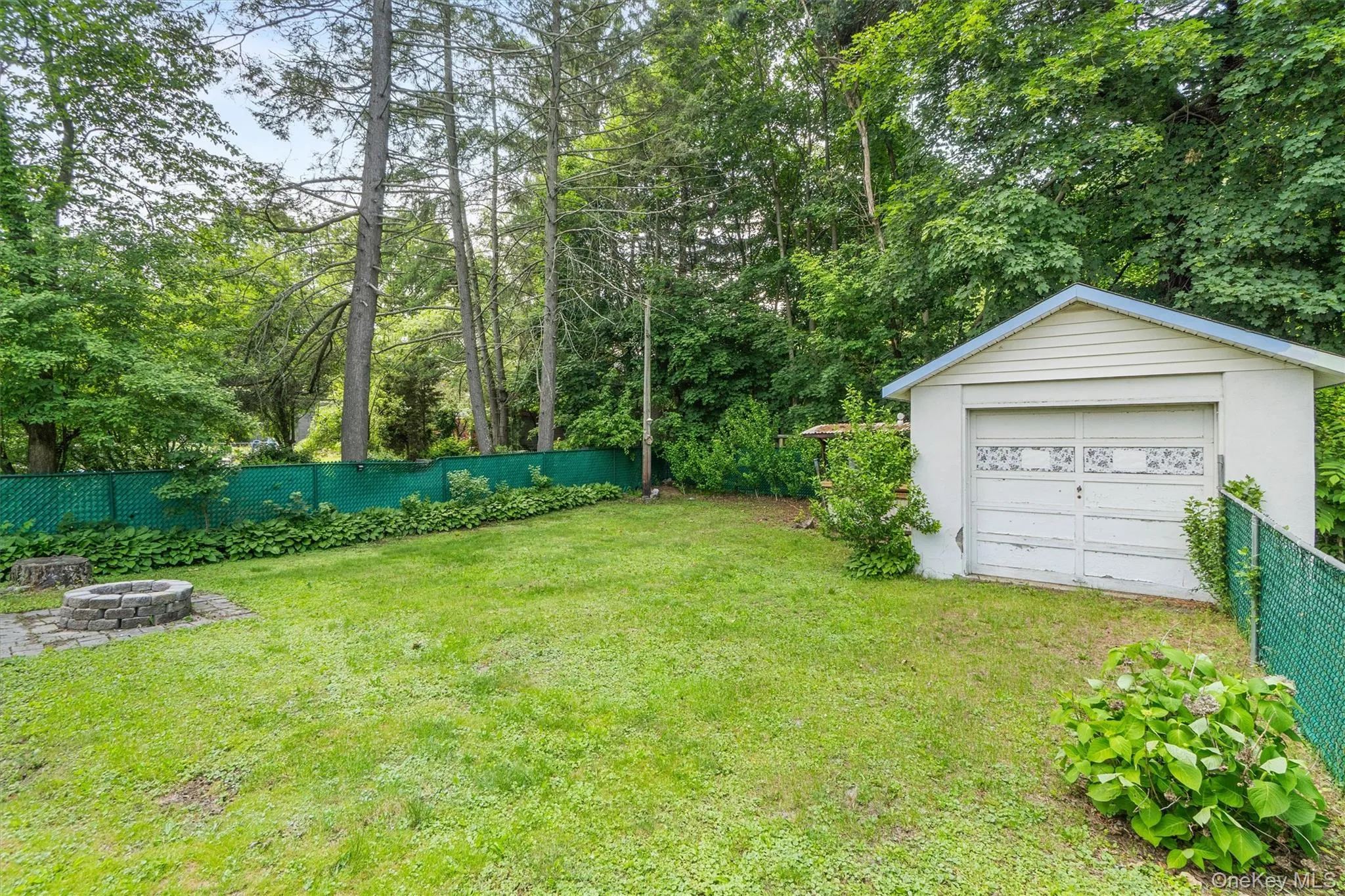 View of yard featuring an outdoor fire pit, an outbuilding, and a garage View of yard featuring an outdoor fire pit, an outbuilding, and a garage