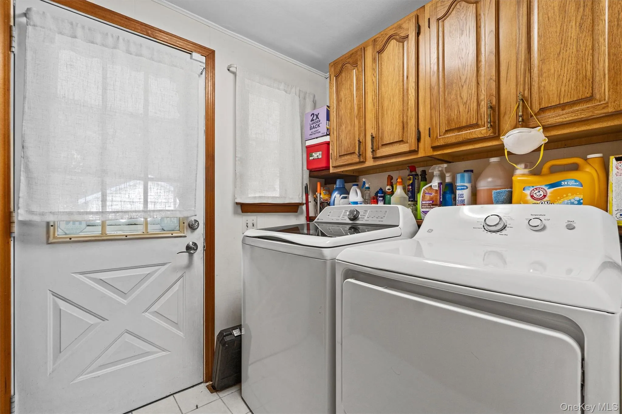 Laundry area with washing machine and clothes dryer, light tile patterned floors, and cabinet space Laundry area with washing machine and clothes dryer, light tile patterned floors, and cabinet space