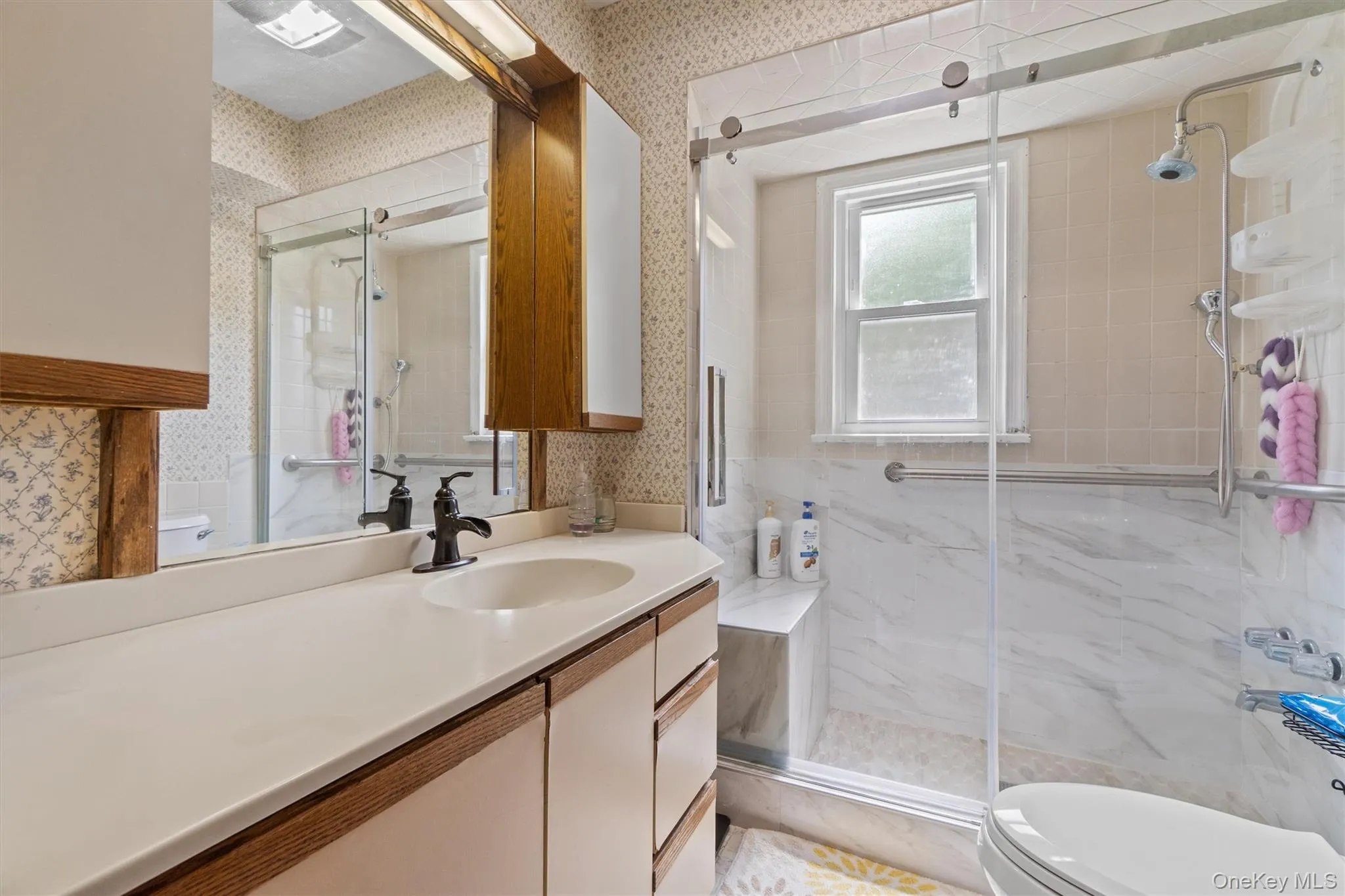 Full bathroom featuring toilet, wallpapered walls, vanity, and a shower stall Full bathroom featuring toilet, wallpapered walls, vanity, and a shower stall