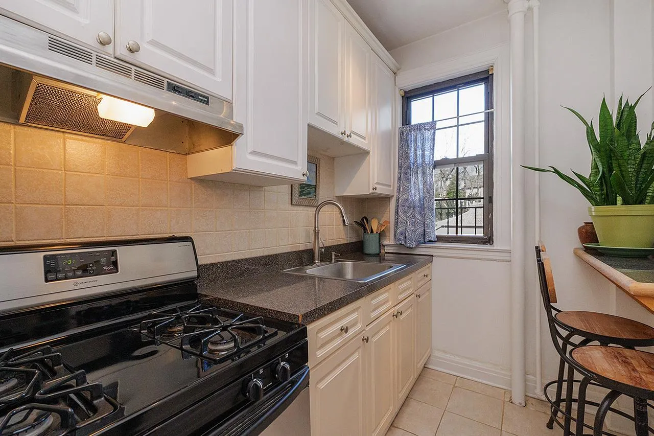 Kitchen featuring gas range oven, under cabinet range hood, a sink, white cabinets, and tasteful backsplash Kitchen featuring gas range oven, under cabinet range hood, a sink, white cabinets, and tasteful backsplash