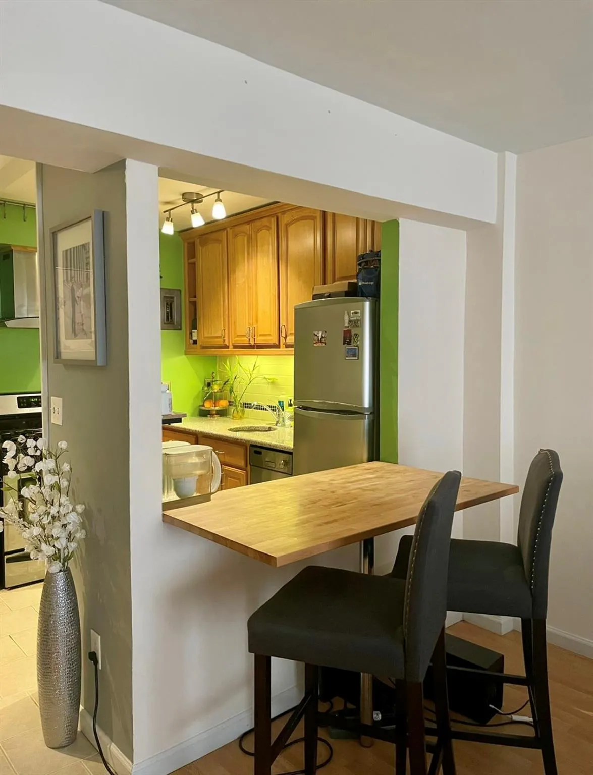 Kitchen featuring stainless steel appliances, a sink, a kitchen breakfast bar, baseboards, and brown cabinets Kitchen featuring stainless steel appliances, a sink, a kitchen breakfast bar, baseboards, and brown cabinets
