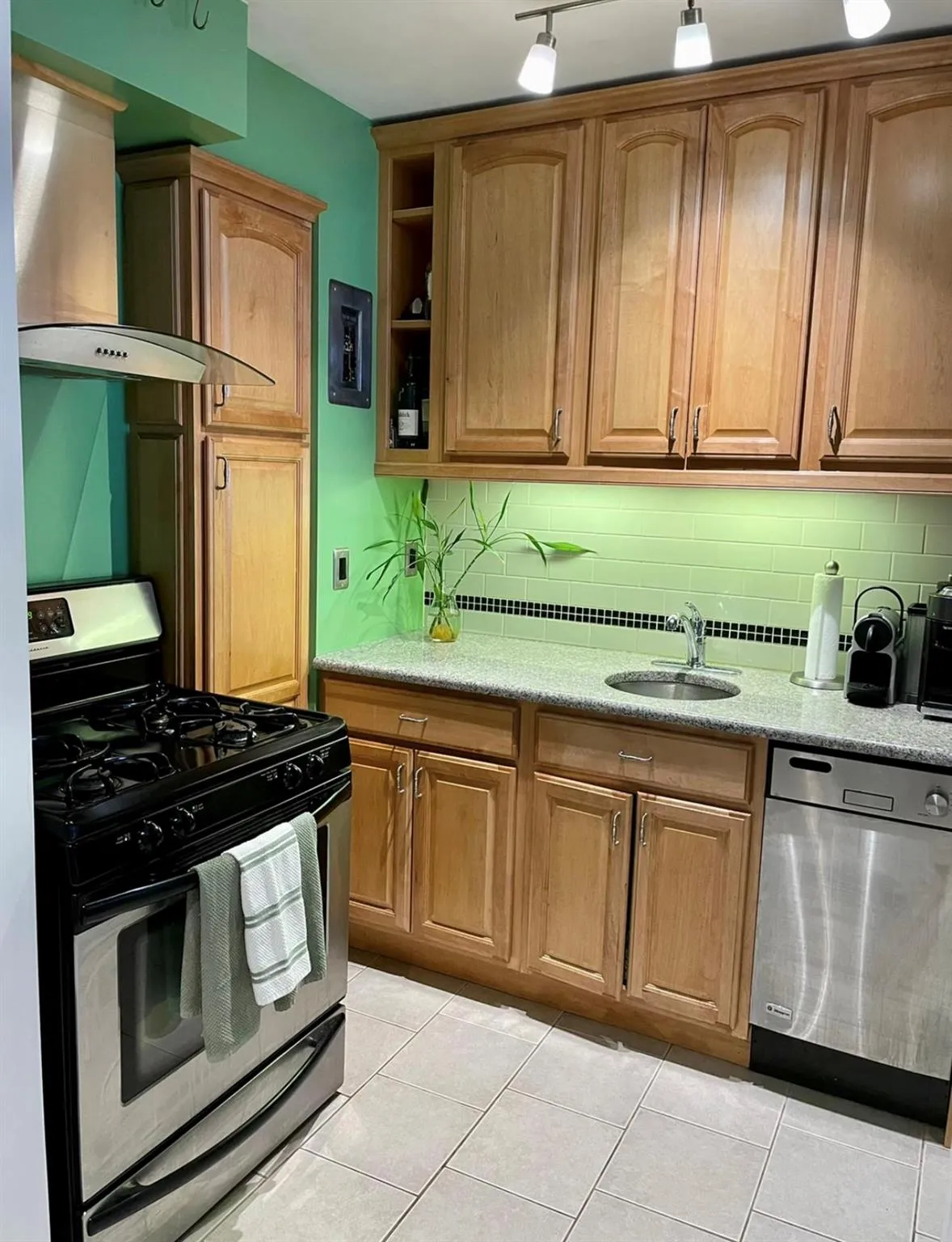 Kitchen featuring appliances with stainless steel finishes, wall chimney exhaust hood, decorative backsplash, and a sink Kitchen featuring appliances with stainless steel finishes, wall chimney exhaust hood, decorative backsplash, and a sink