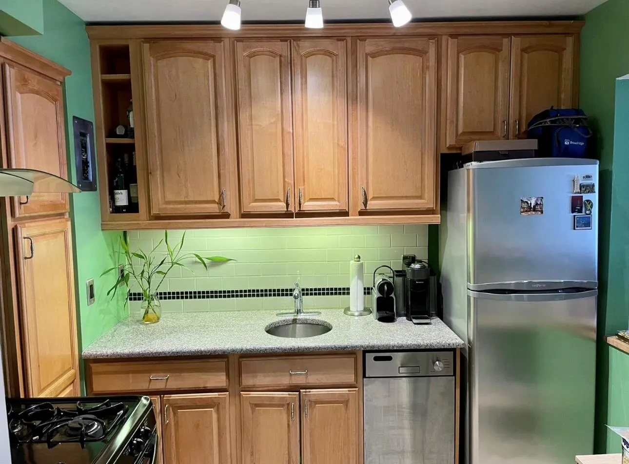 Kitchen with freestanding refrigerator, a sink, tasteful backsplash, and light stone countertops Kitchen with freestanding refrigerator, a sink, tasteful backsplash, and light stone countertops