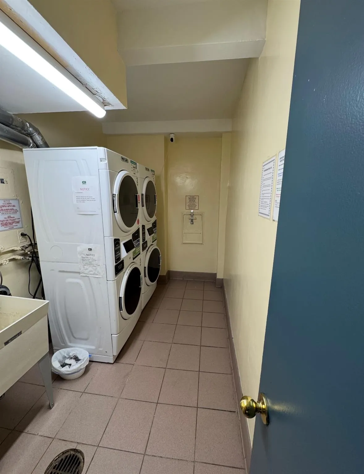 Communal laundry room with stacked washer / drying machine, light tile patterned floors, and washing machine and clothes dryer Communal laundry room with stacked washer / drying machine, light tile patterned floors, and washing machine and clothes dryer