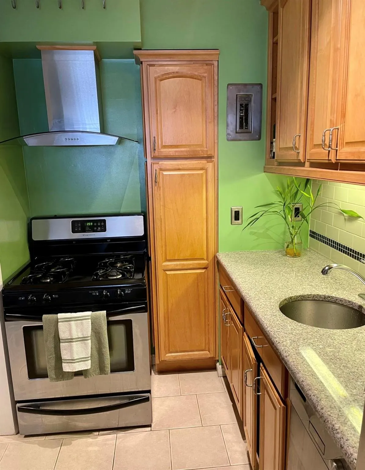 Kitchen featuring stainless steel range with gas cooktop, wall chimney range hood, a sink, decorative backsplash, and light stone counters Kitchen featuring stainless steel range with gas cooktop, wall chimney range hood, a sink, decorative backsplash, and light stone counters