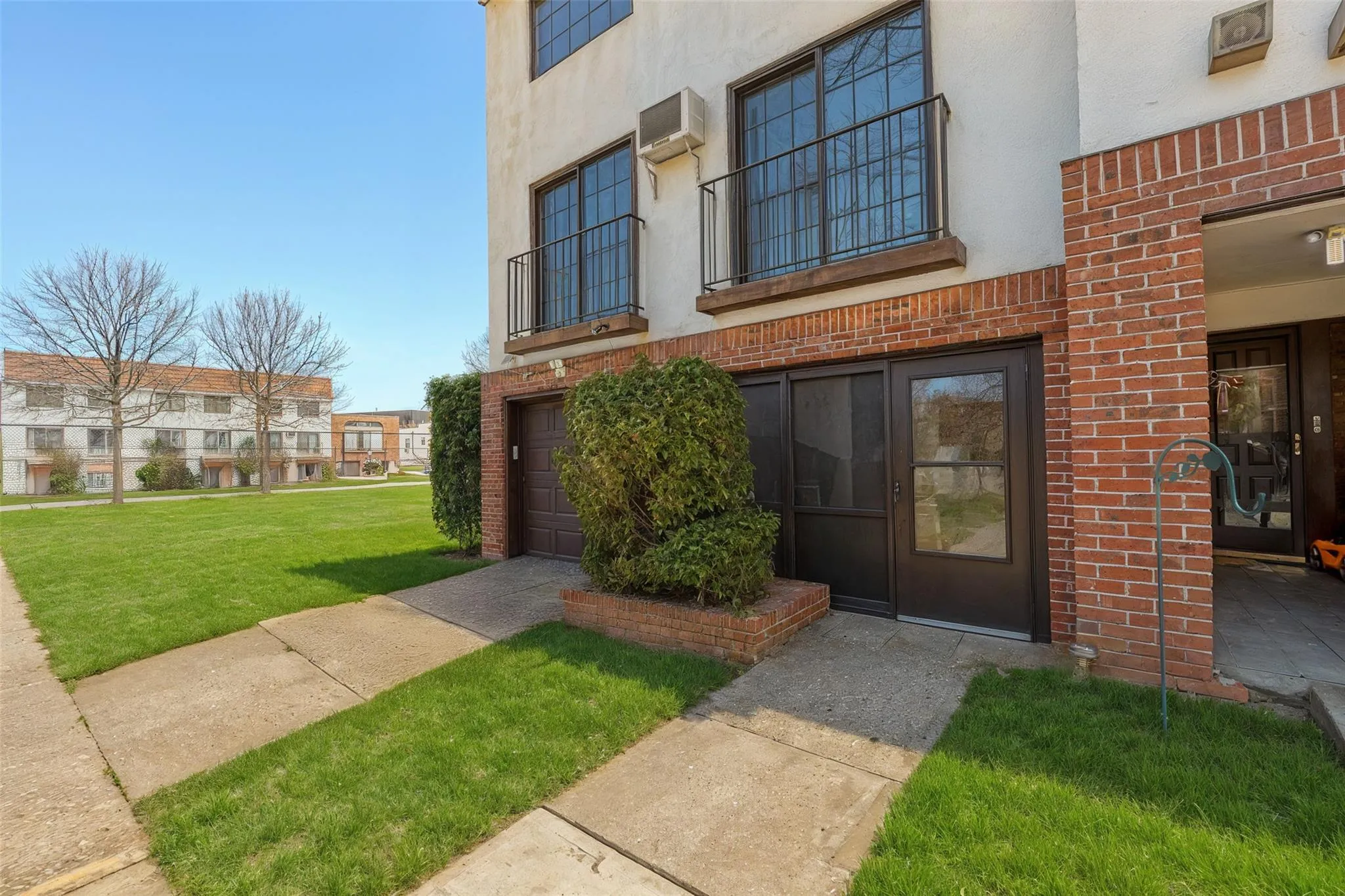 Property entrance with stucco siding, brick siding, a lawn, and a wall unit AC Property entrance with stucco siding, brick siding, a lawn, and a wall unit AC