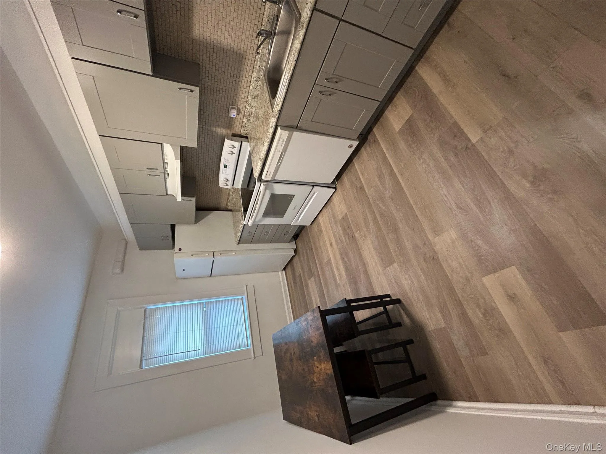 Kitchen featuring gray cabinets, backsplash, range, dishwasher, and light wood finished floors Kitchen featuring gray cabinets, backsplash, range, dishwasher, and light wood finished floors
