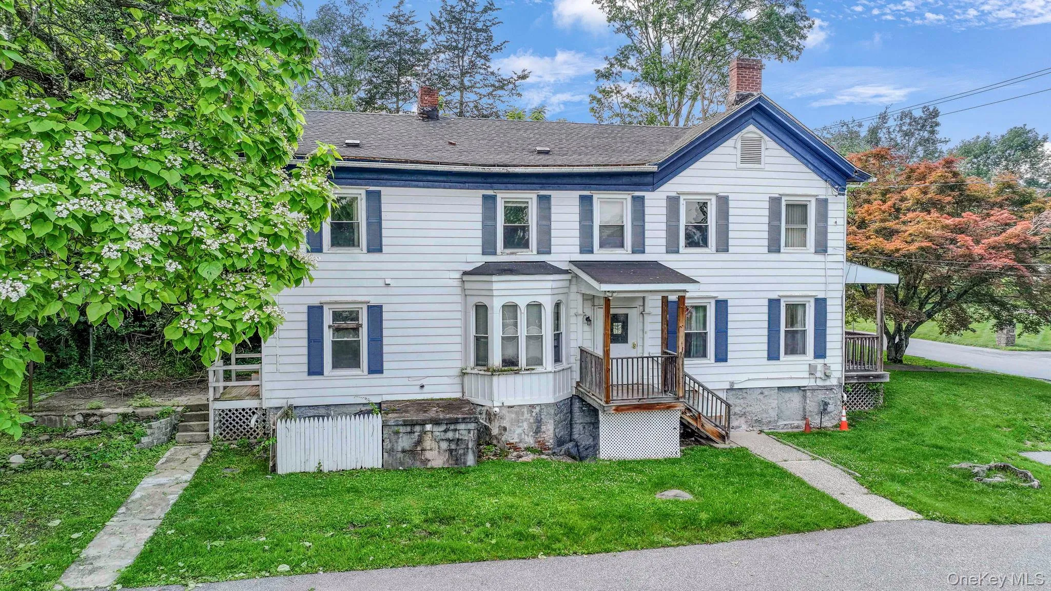 Townhome / multi-family property featuring a chimney, a front yard, and a shingled roof Townhome / multi-family property featuring a chimney, a front yard, and a shingled roof
