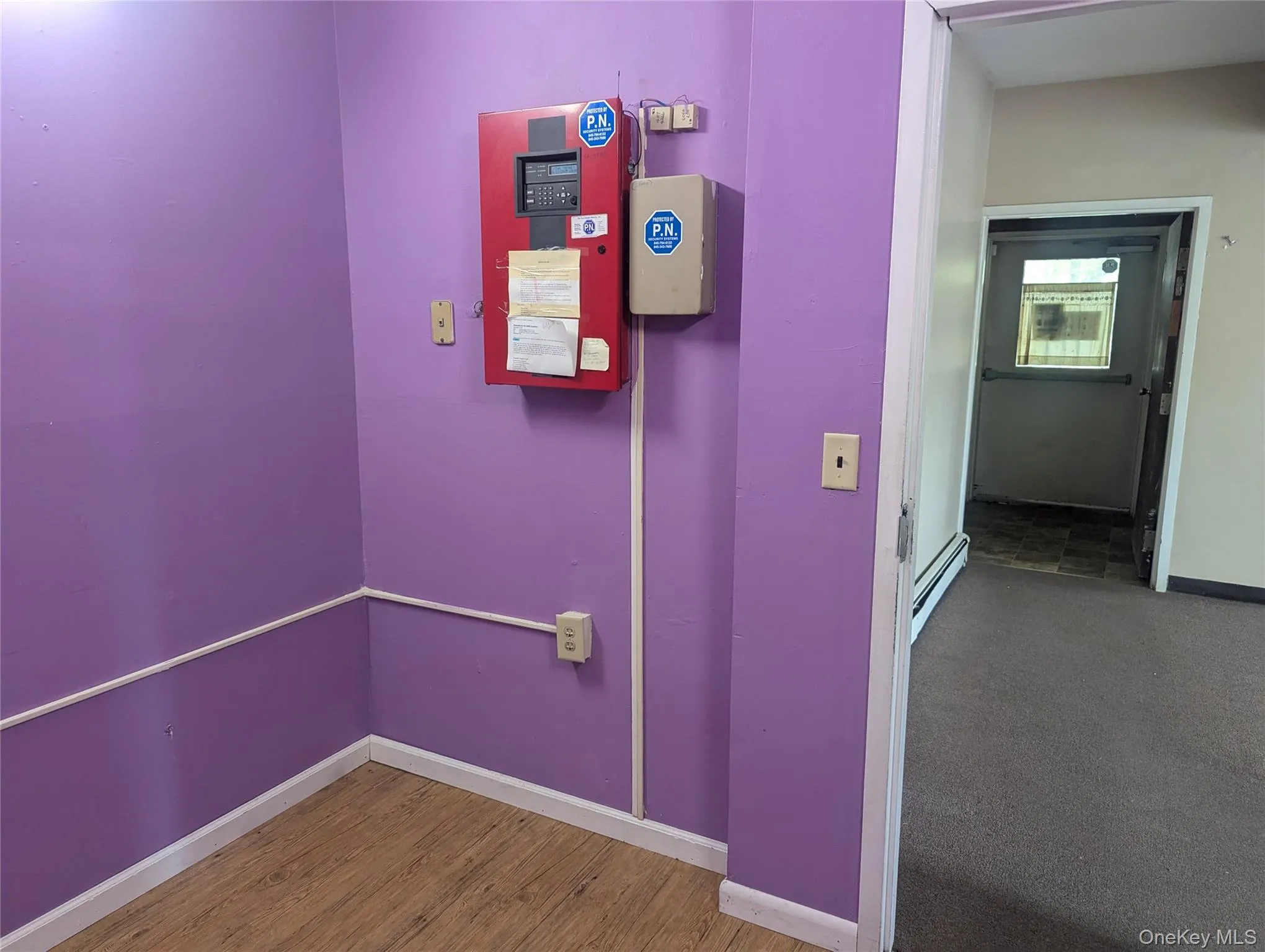 Hallway with baseboard heating and wood finished floors Hallway with baseboard heating and wood finished floors