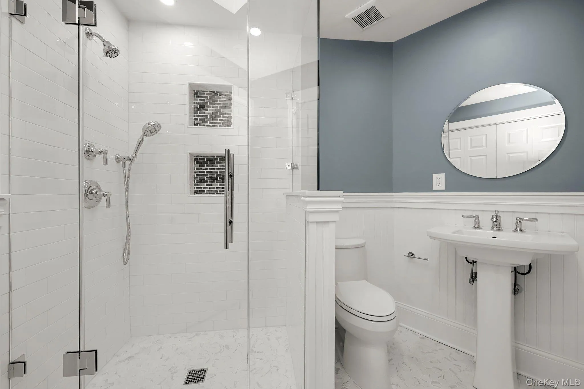 Bathroom with a stall shower, marble finish floors, toilet, wainscoting, and recessed lighting Bathroom with a stall shower, marble finish floors, toilet, wainscoting, and recessed lighting