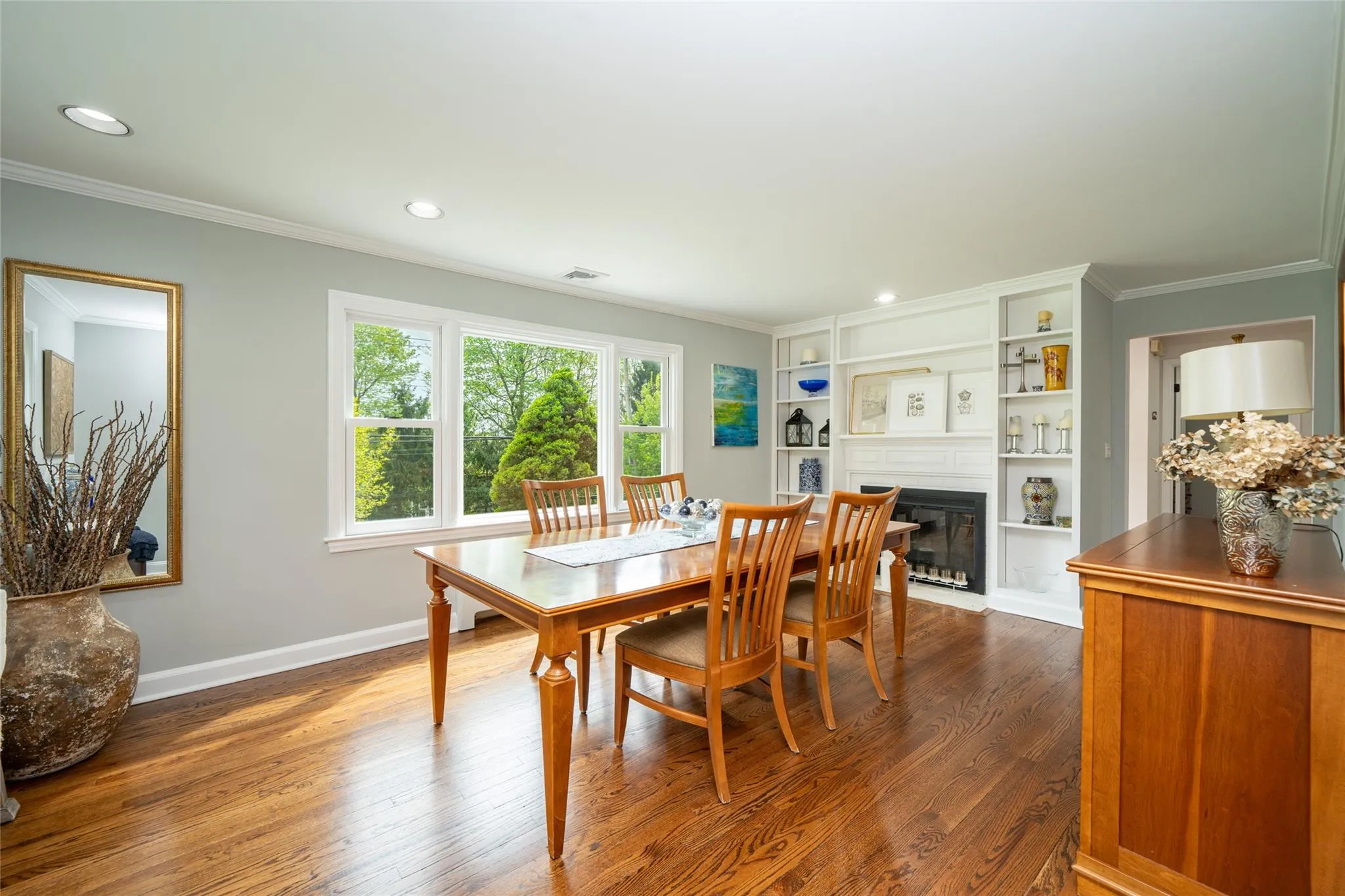 Dining area with ornamental molding, dark wood-type flooring, a fireplace with flush hearth, and recessed lighting Dining area with ornamental molding, dark wood-type flooring, a fireplace with flush hearth, and recessed lighting