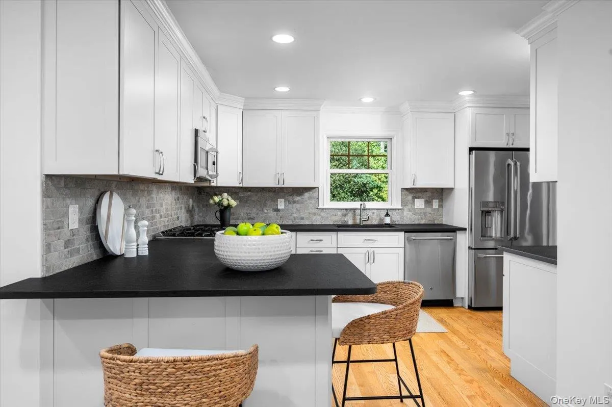 White Shaker cabinetry, leathered granite countertops, stainless steel appliances and oak flooring give the renovated kitchen a crisp, timeless look. White Shaker cabinetry, leathered granite countertops, stainless steel appliances and oak flooring give the renovated kitchen a crisp, timeless look.