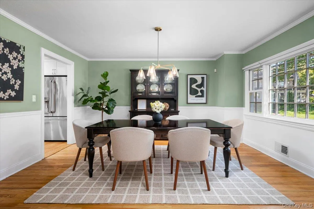 A large picture window fills the dining room with natural light, while crown molding and hardwood floors add timeless architectural detail. A large picture window fills the dining room with natural light, while crown molding and hardwood floors add timeless architectural detail.